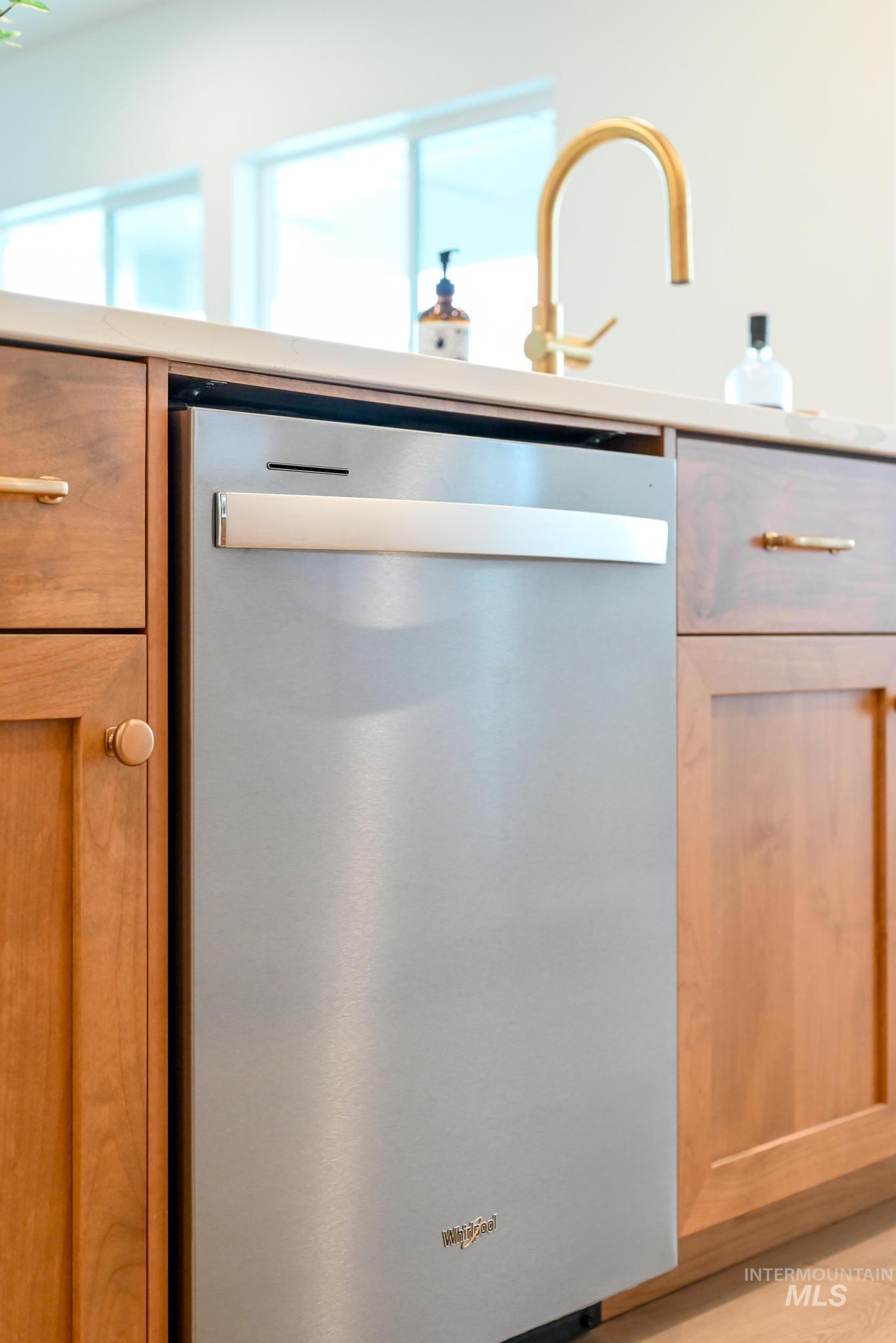 Kitchen view of stainless steel dishwasher and light countertops