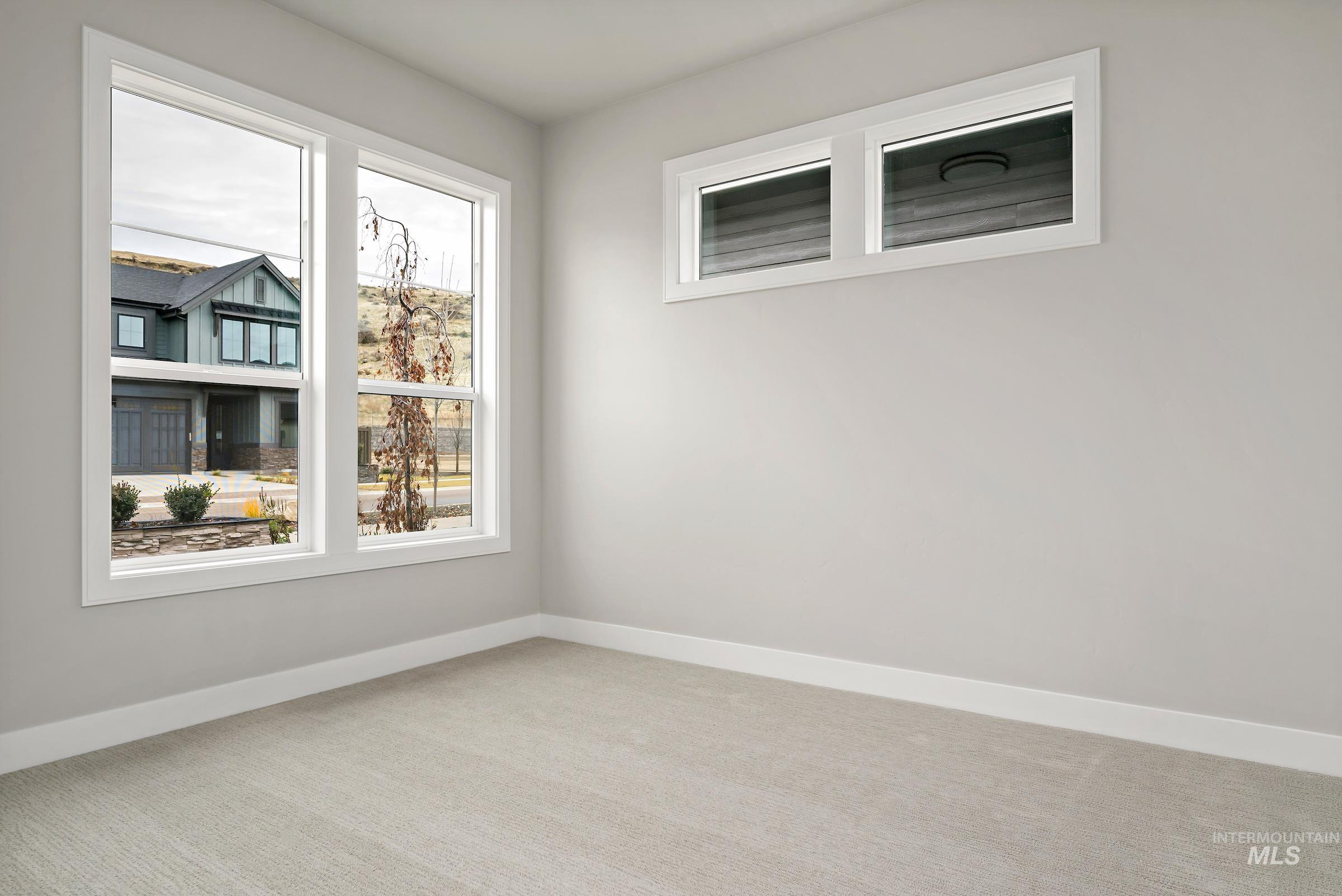 Carpeted spare room featuring baseboards