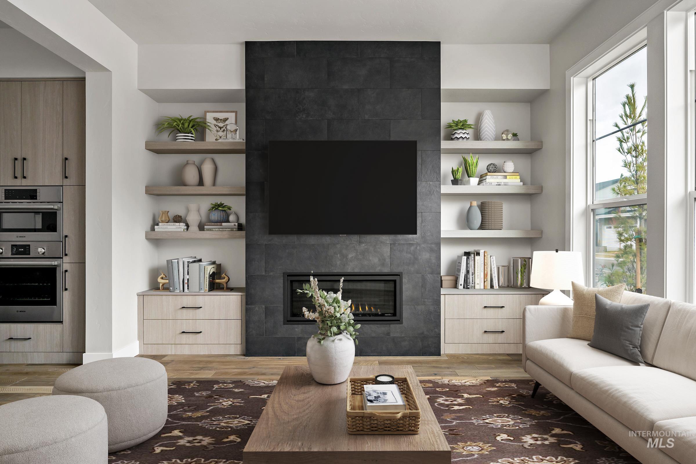 Living area with built in features, a tile fireplace, and light wood finished floors