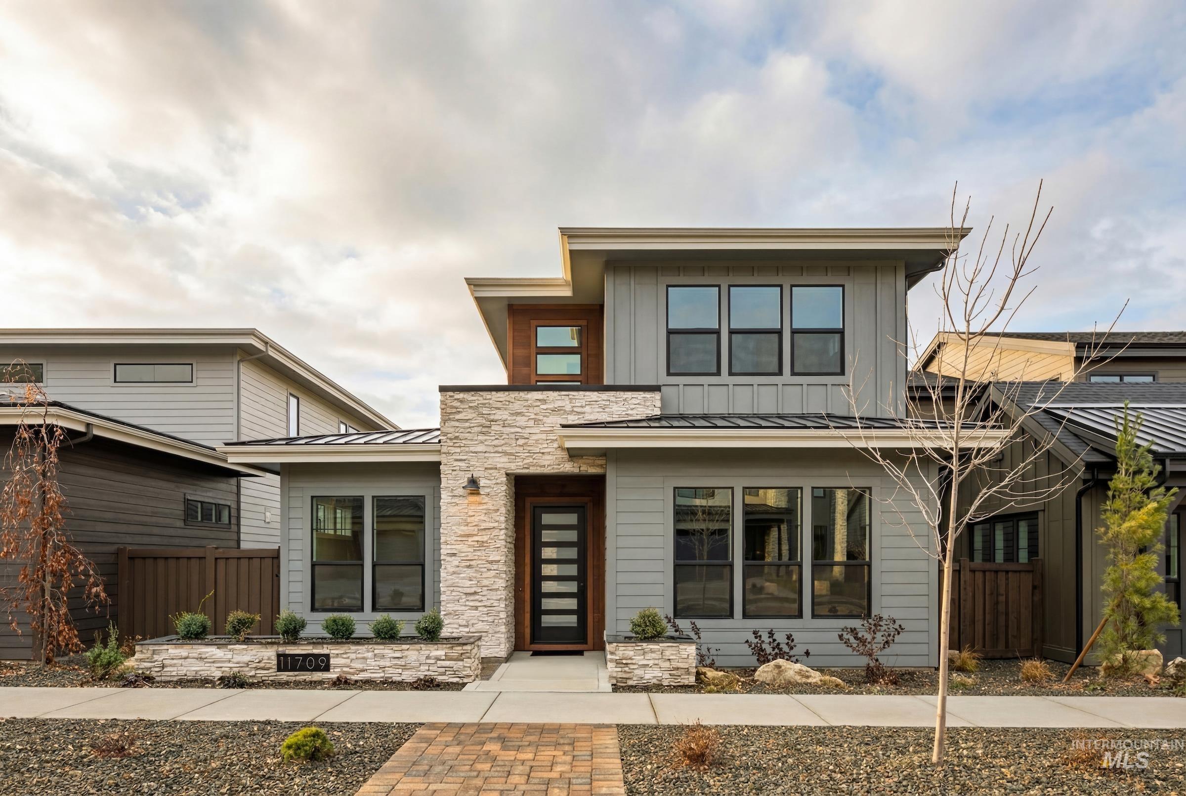 Modern home featuring a standing seam roof, a metal roof, and stone siding