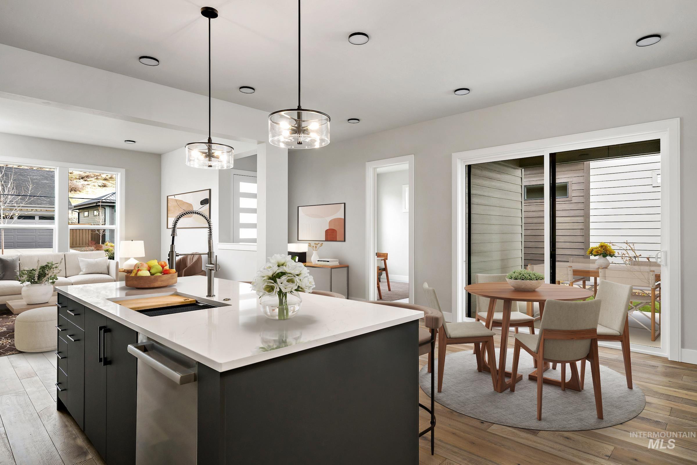 Kitchen with decorative light fixtures, light wood-style floors, dark cabinetry, a center island with sink, and recessed lighting
