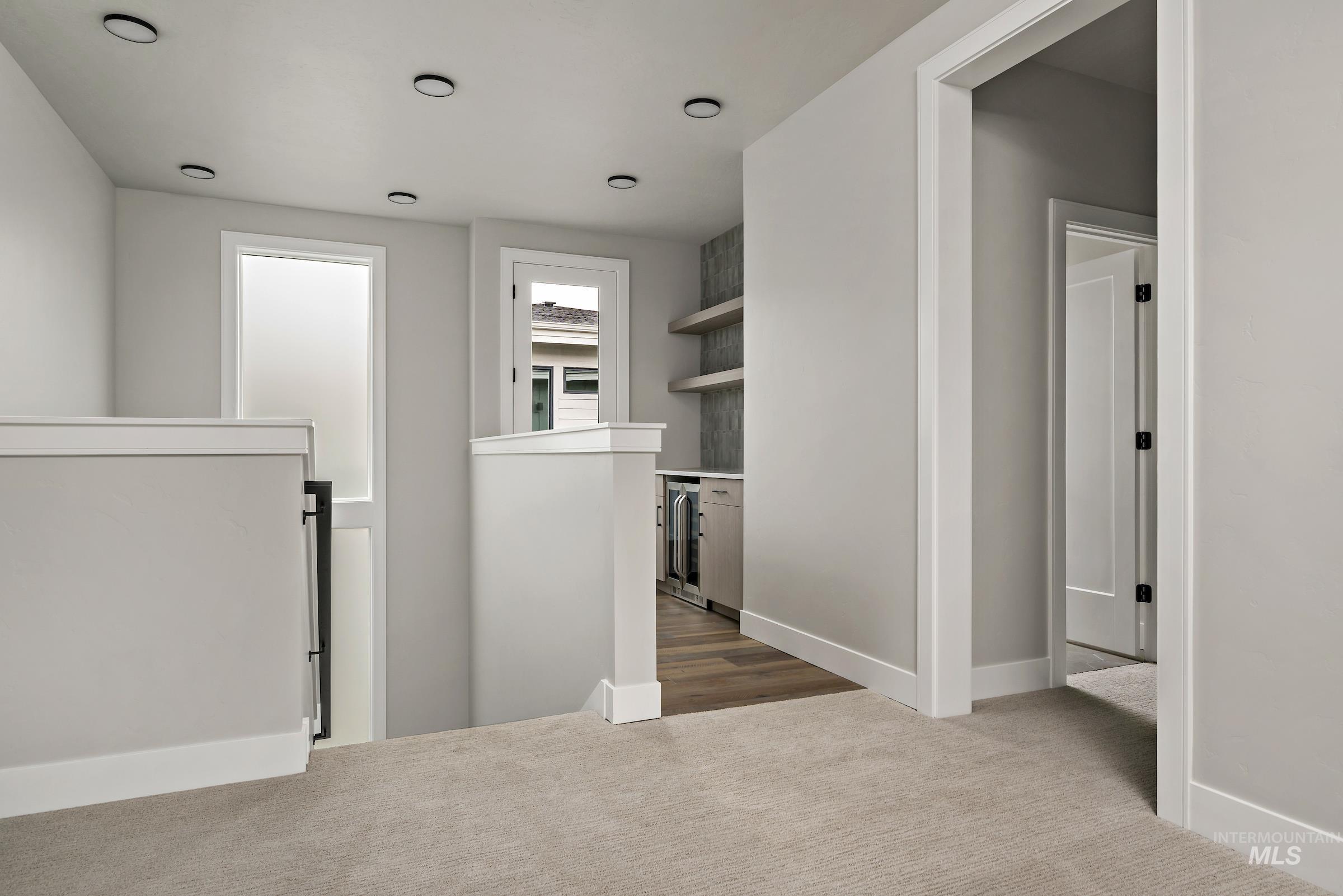 Corridor with an upstairs landing, dark carpet, and wine cooler