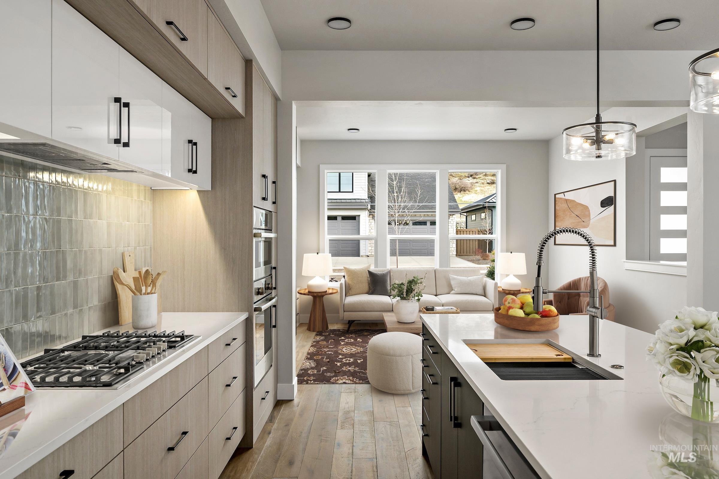 Kitchen featuring decorative backsplash, hanging light fixtures, open floor plan, modern cabinets, and appliances with stainless steel finishes