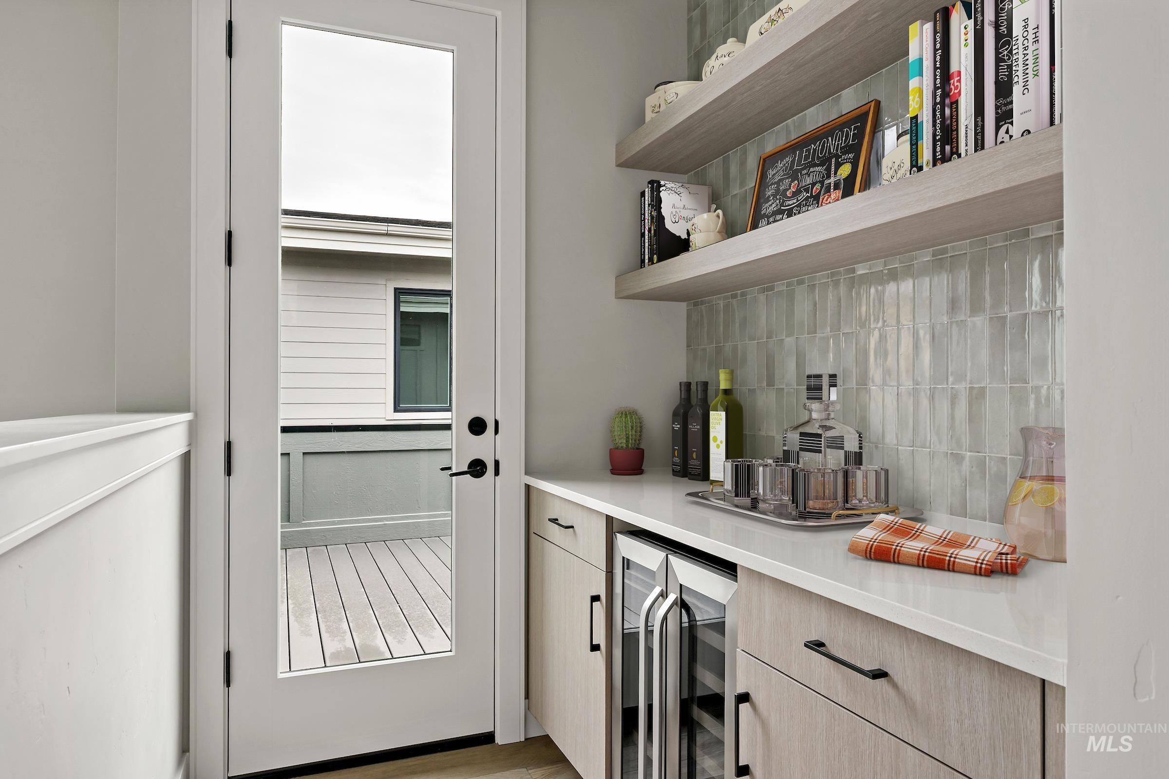 Bar area featuring decorative backsplash, wine cooler, light countertops, and light brown cabinets