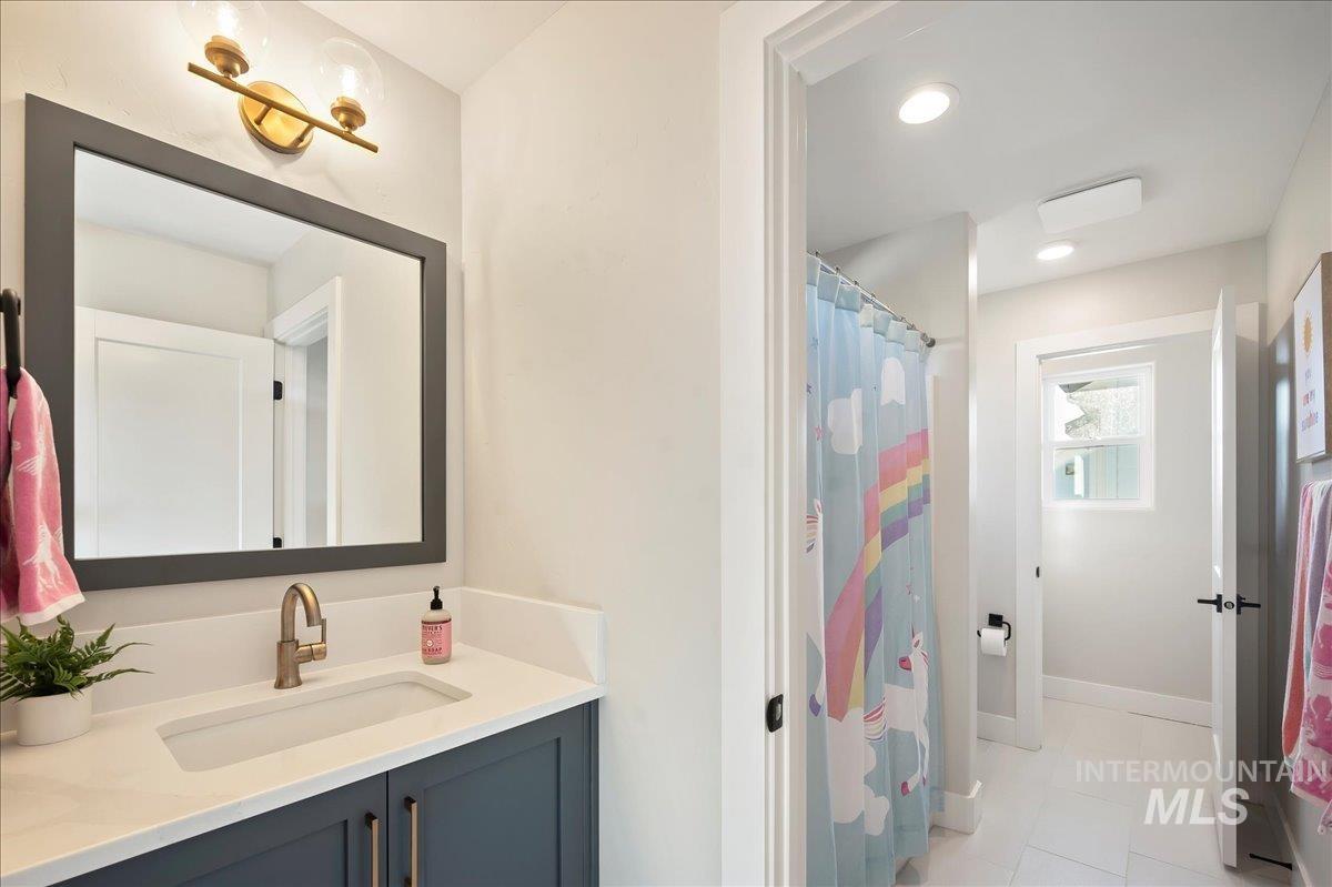 Full bath with vanity, curtained shower, and recessed lighting
