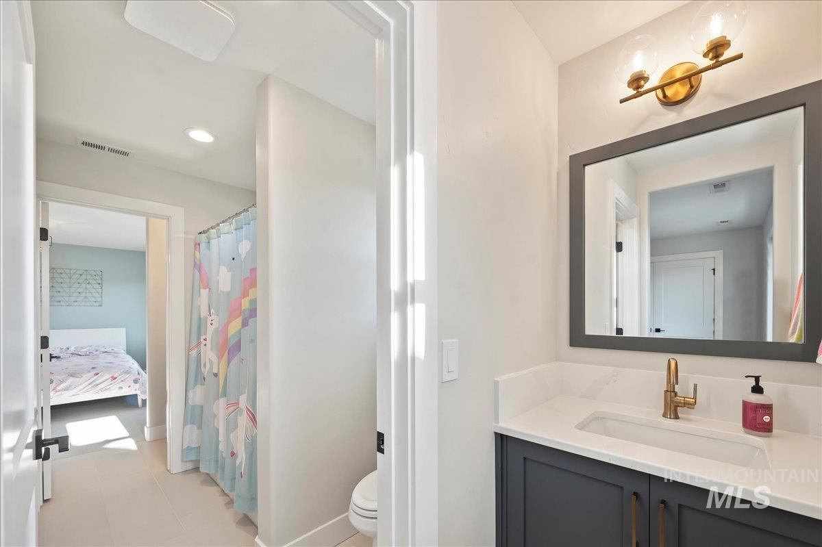 Ensuite bathroom featuring vanity, curtained shower, and recessed lighting