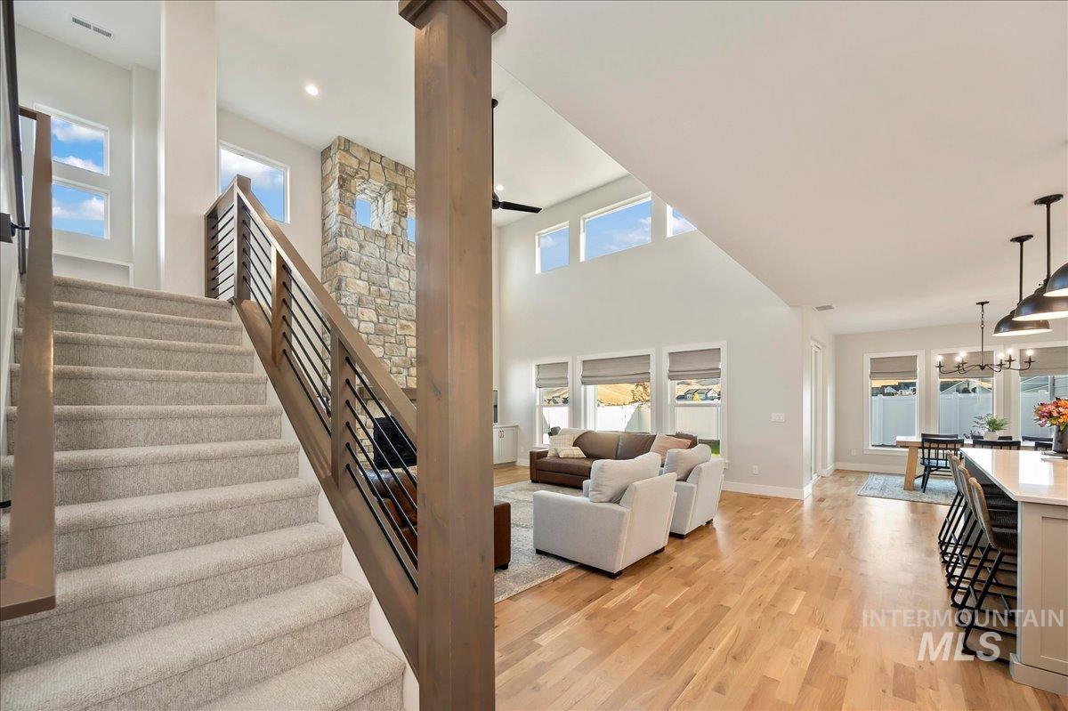 Stairway with a high ceiling, wood finished floors, healthy amount of natural light, and hanging lights