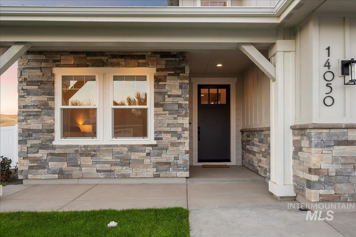 View of exterior entry featuring stone siding, covered porch, and board and batten siding