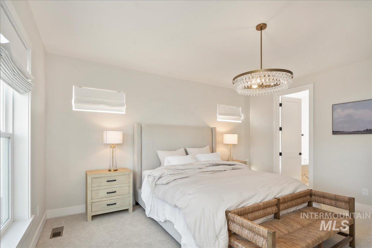 Carpeted bedroom featuring a chandelier and ensuite bath
