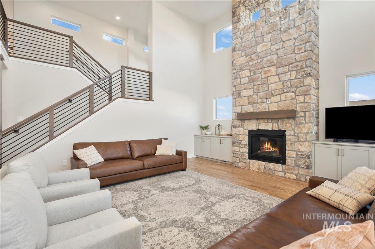 Living area featuring a high ceiling, light wood-style flooring, and a stone fireplace