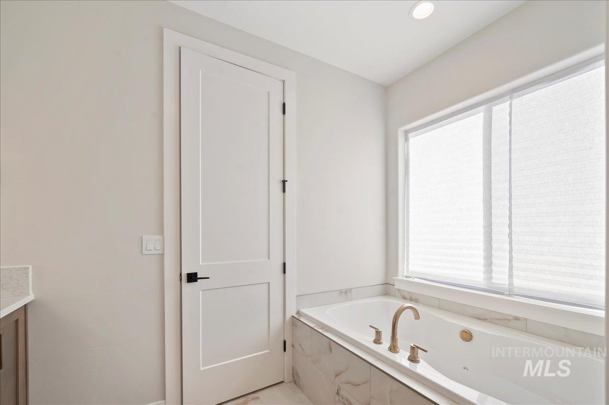 Bathroom featuring a bath, vanity, and recessed lighting