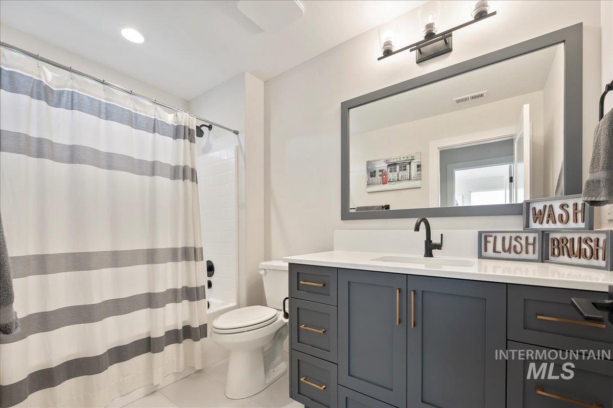Full bath featuring vanity, shower / tub combo, and light tile patterned flooring