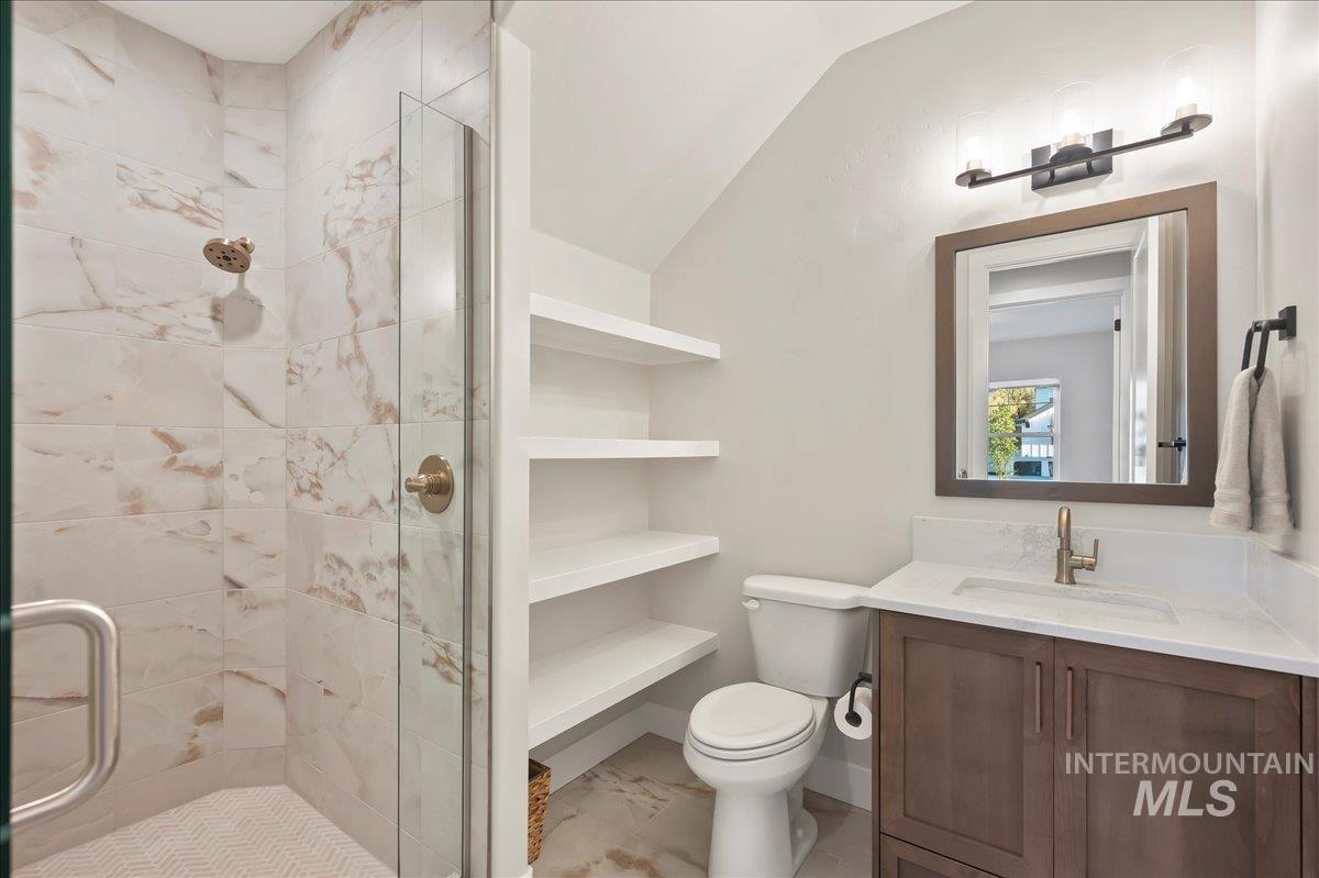 Full bathroom featuring a marble finish shower, vanity, vaulted ceiling, and light marble finish flooring