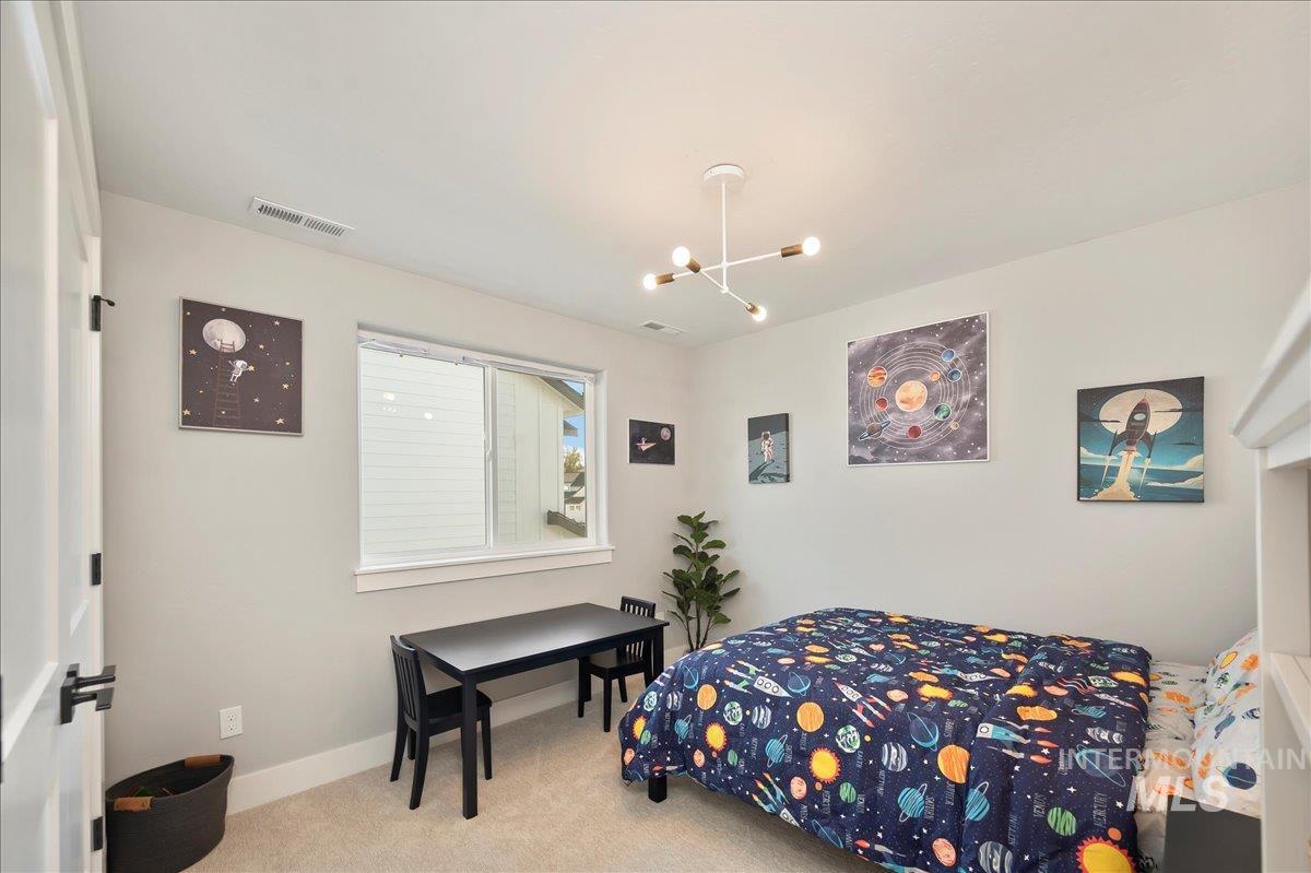 Carpeted bedroom with baseboards and a chandelier
