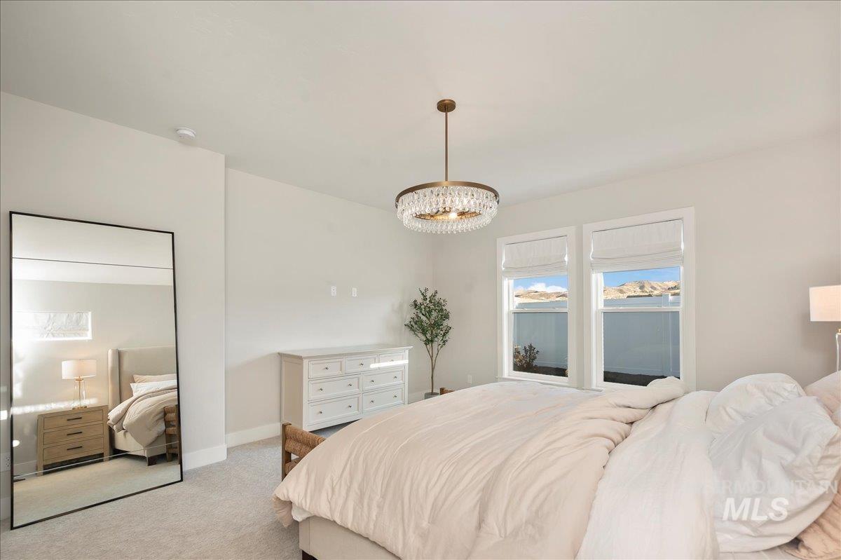 Bedroom with light colored carpet and hanging lights