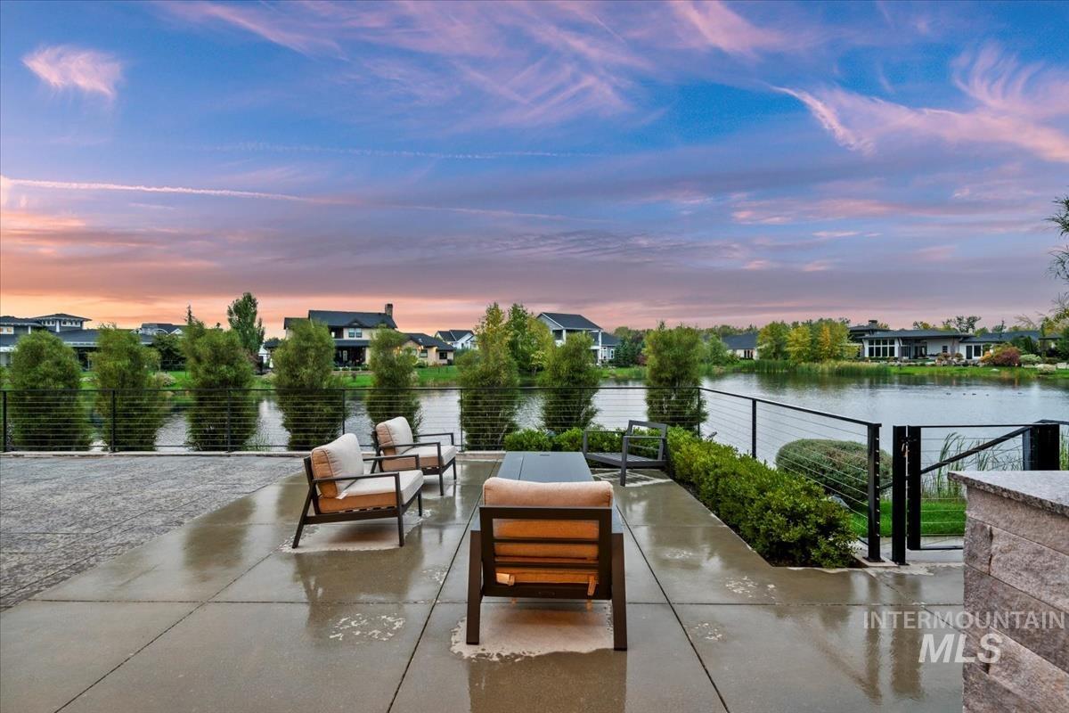 Patio terrace at dusk featuring a water view and an outdoor living space