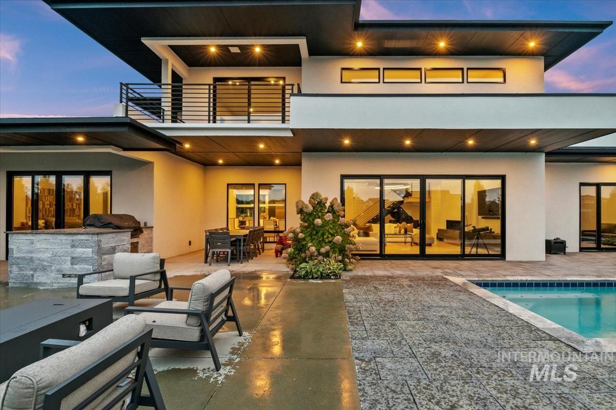 Back of property featuring stucco siding, an outdoor pool, and a patio area