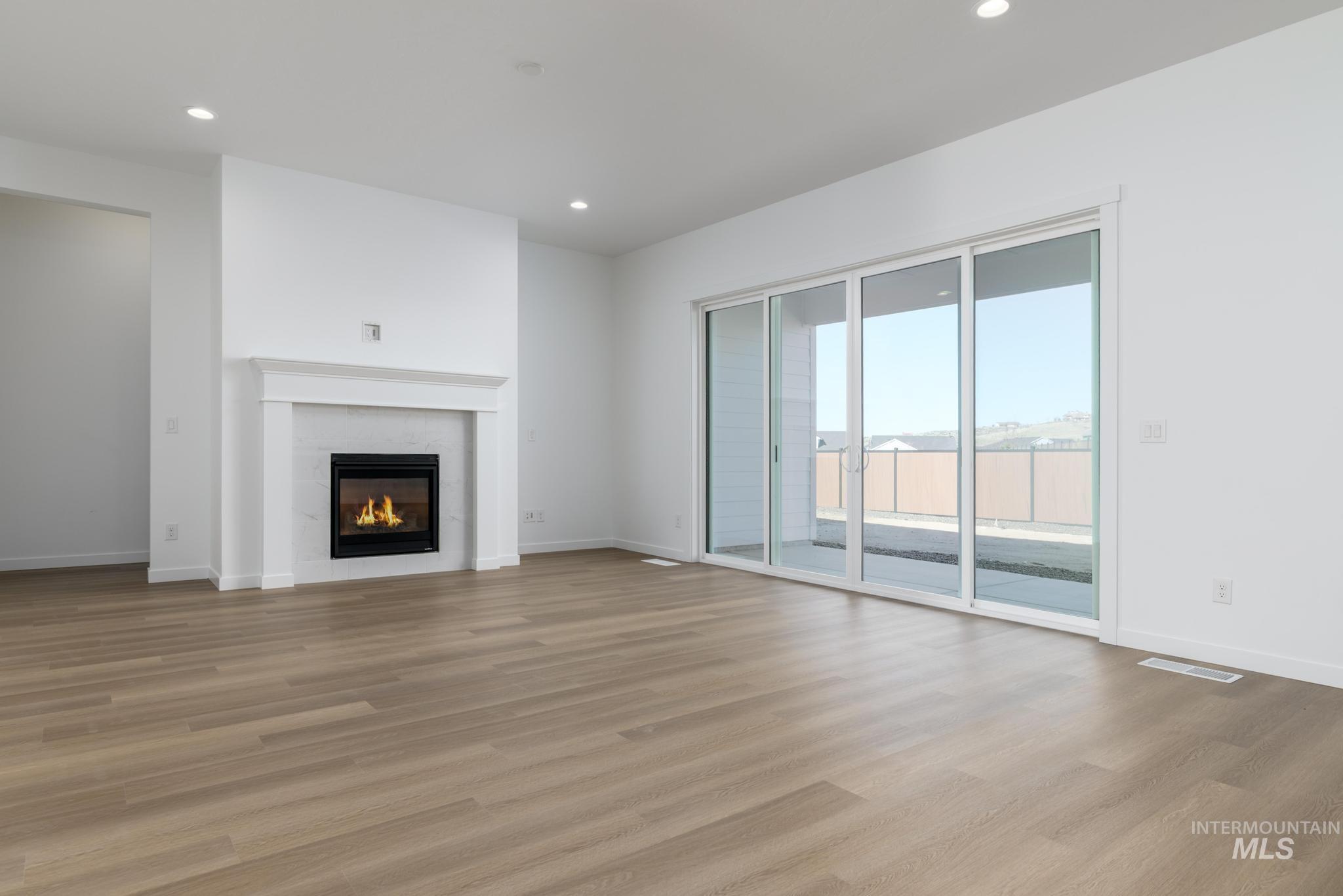 Unfurnished living room with recessed lighting, light wood-style flooring, and a tiled fireplace