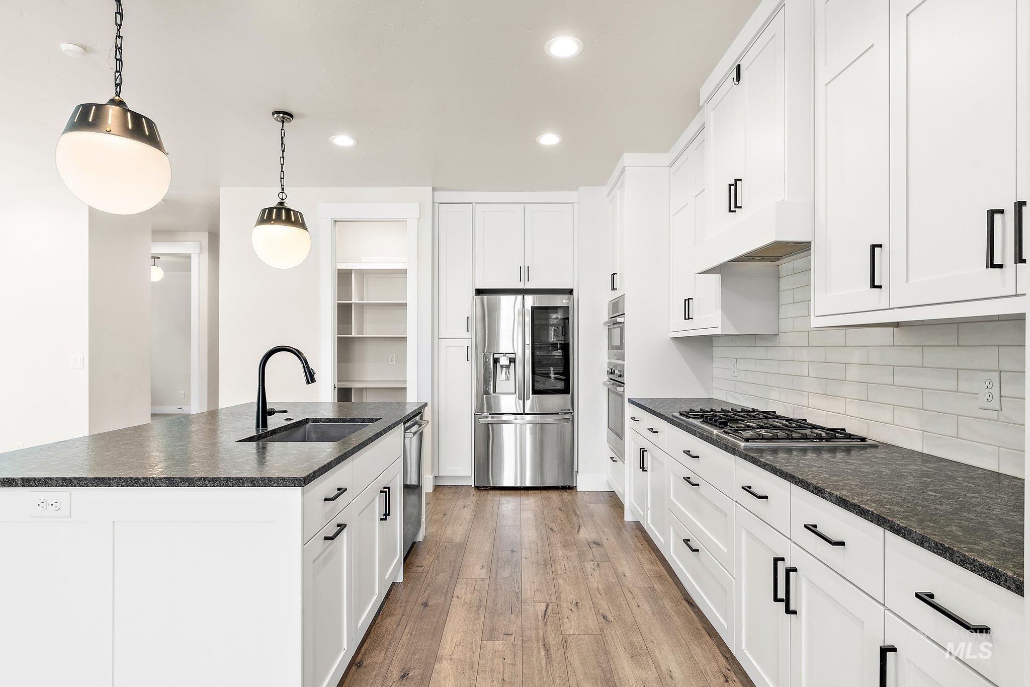 Kitchen with recessed lighting, stainless steel appliances, a center island with sink, pendant lighting, and light wood-style flooring