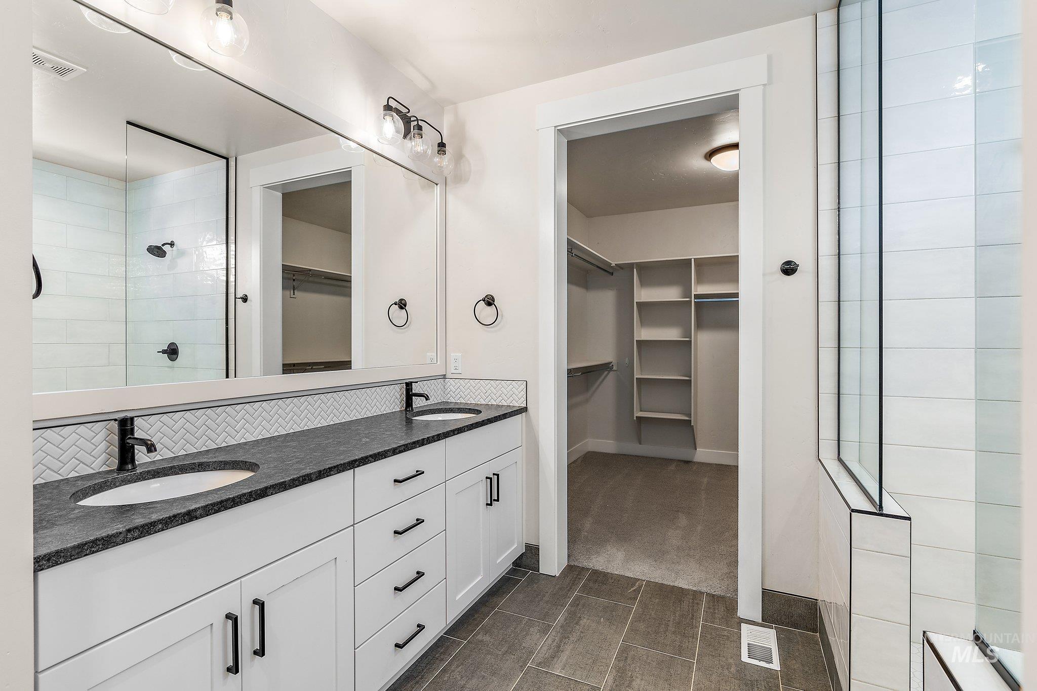Full bathroom featuring a walk in closet, a walk in shower, and double vanity