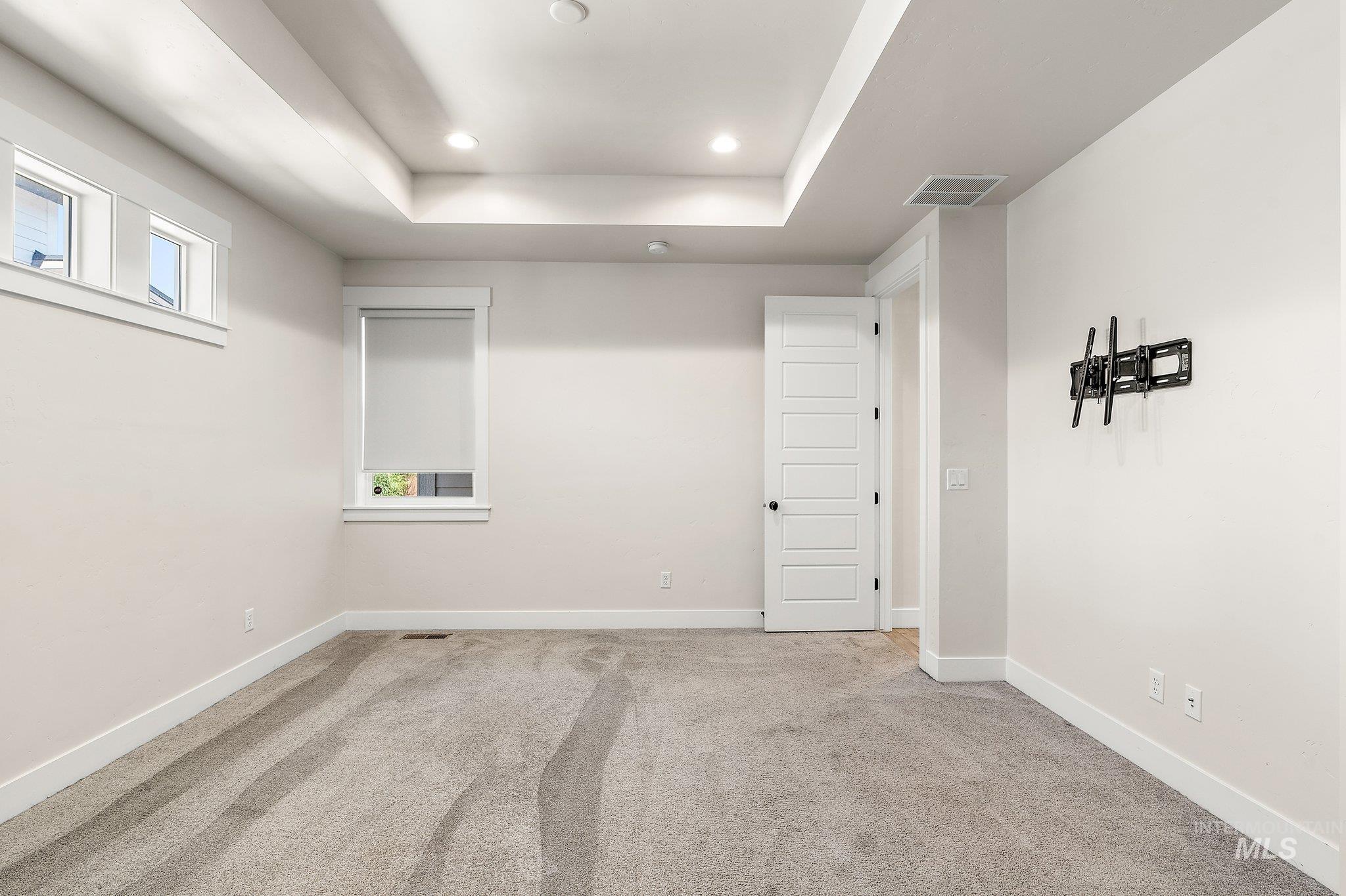 Carpeted spare room with a tray ceiling and recessed lighting