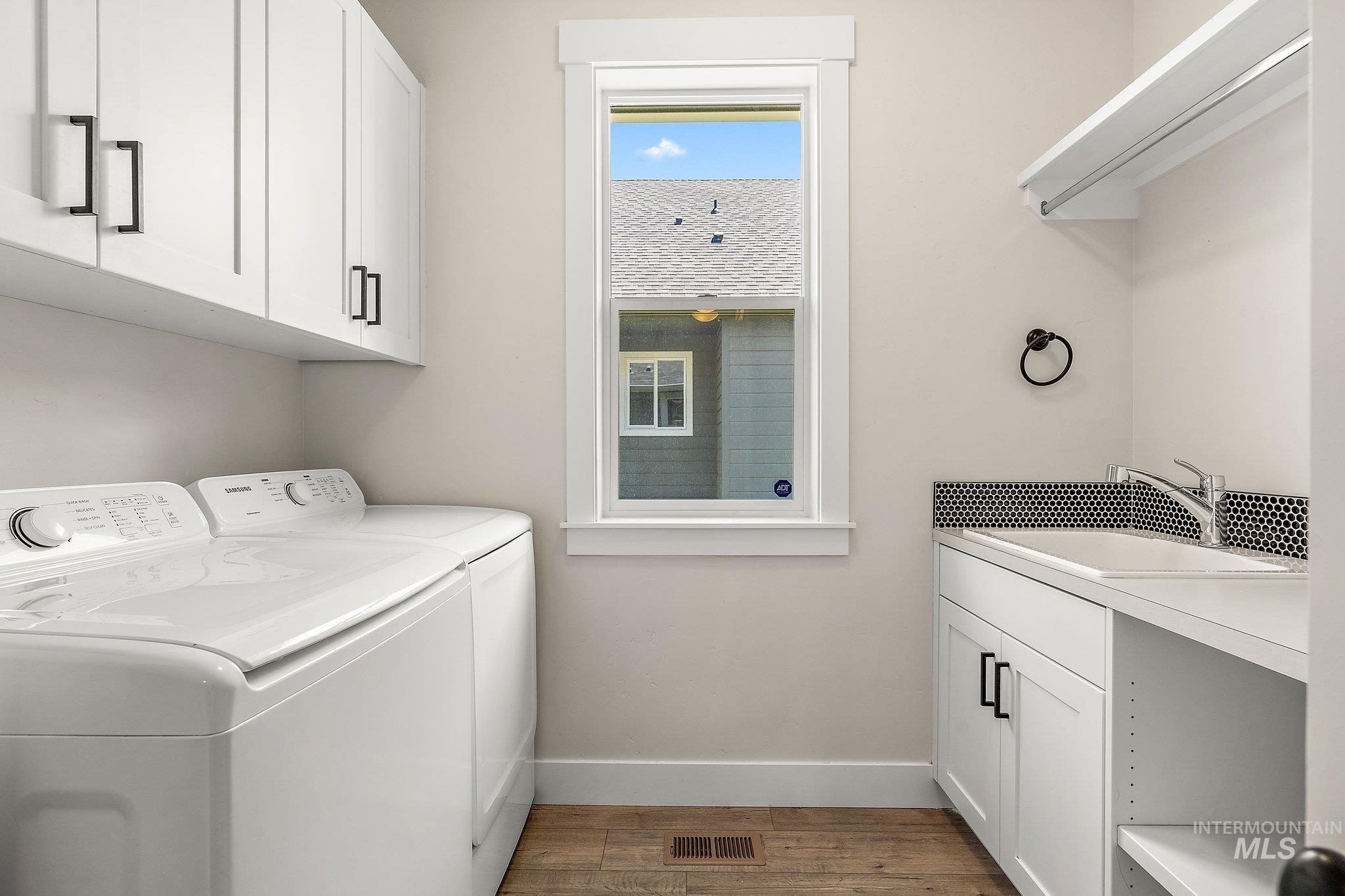 Laundry area featuring cabinet space, wood finished floors, and washing machine and dryer
