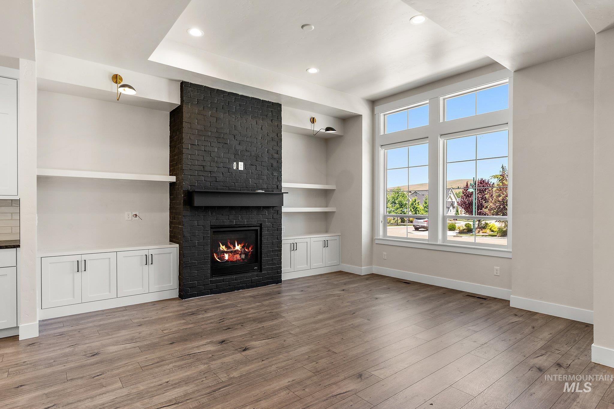 Unfurnished living room with a brick fireplace, recessed lighting, and light wood-style floors