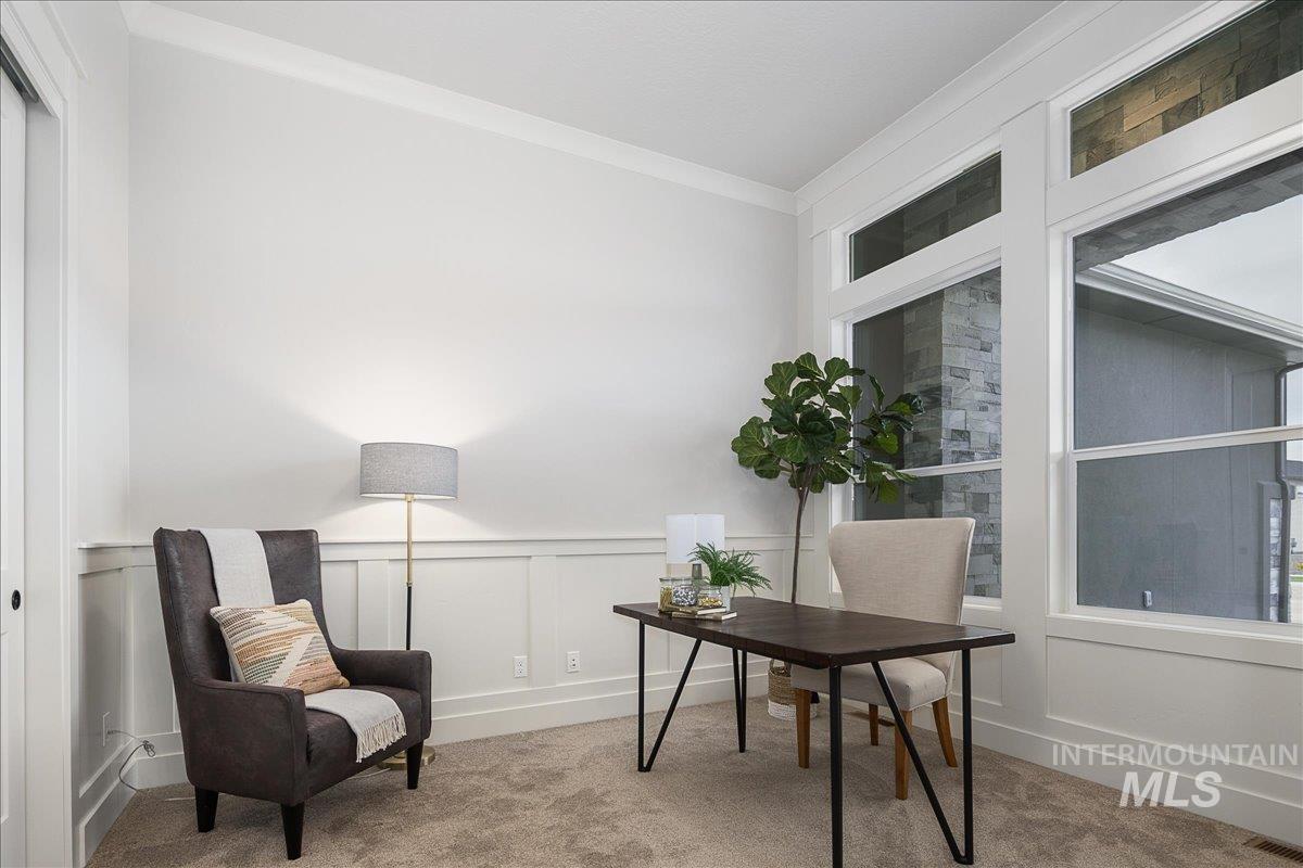 Office area featuring crown molding, carpet flooring, a decorative wall, and a wainscoted wall