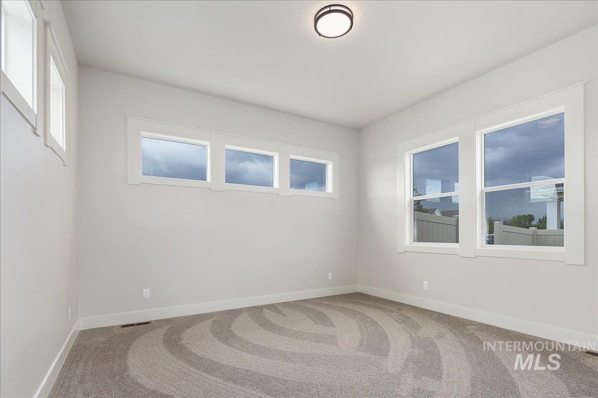 Spare room featuring light carpet and baseboards