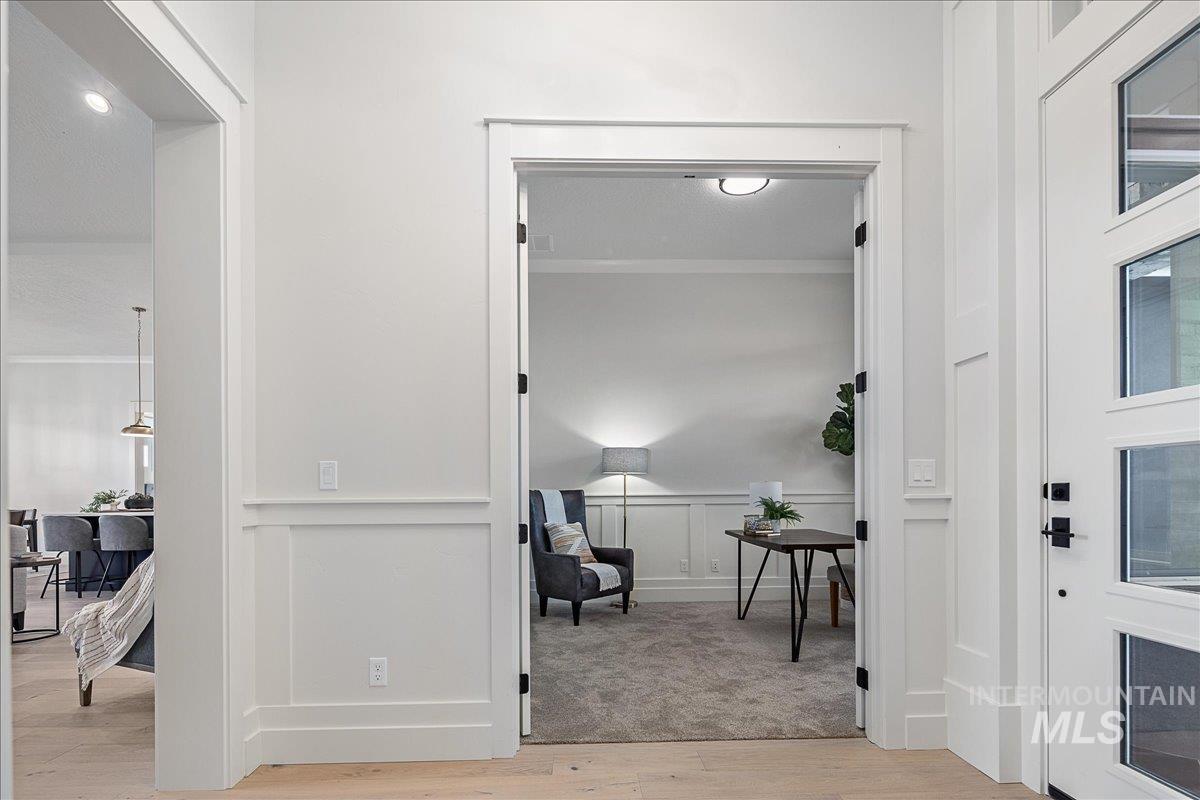 Entryway with ornamental molding, a decorative wall, and light wood finished floors