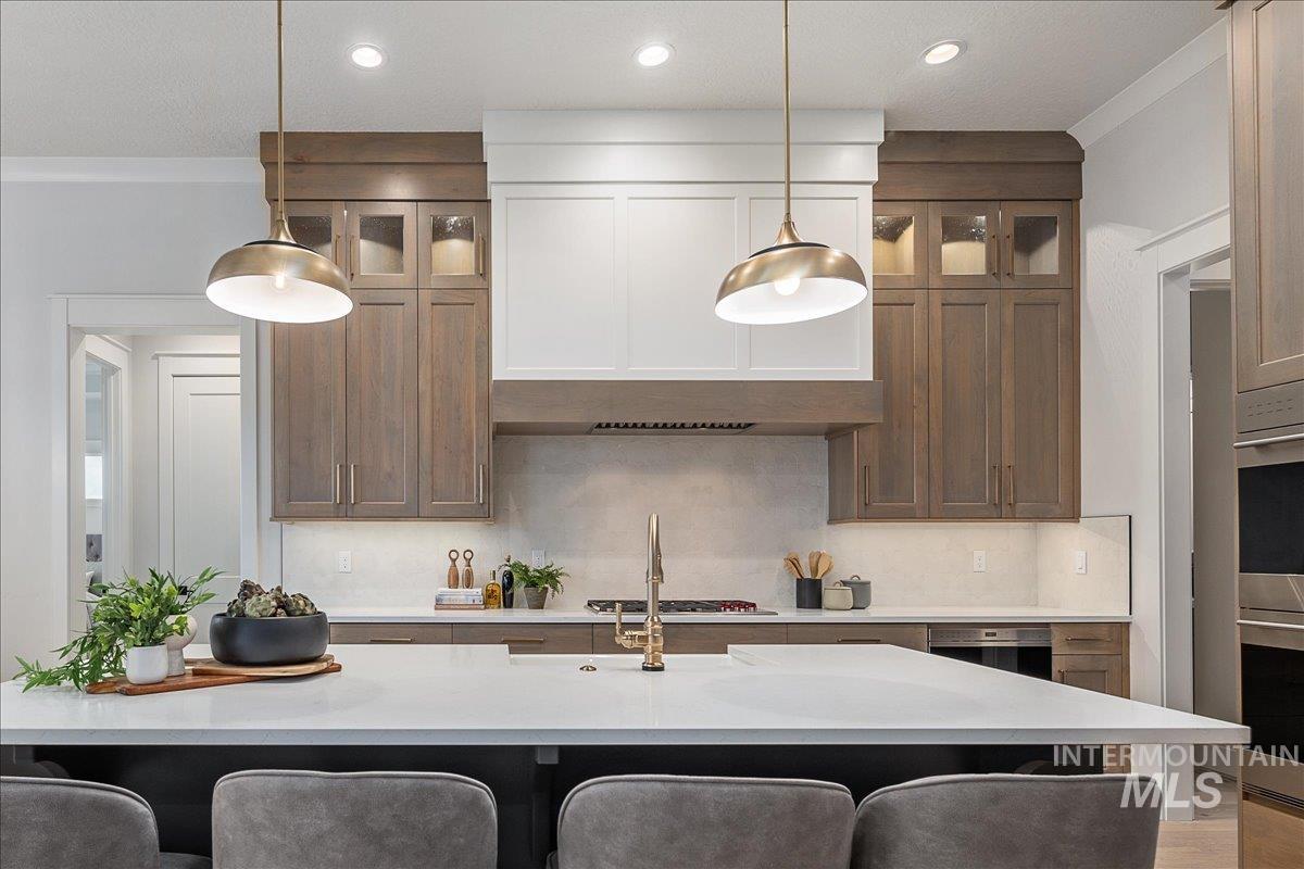 Kitchen featuring glass insert cabinets, a kitchen breakfast bar, brown cabinetry, and stainless steel appliances