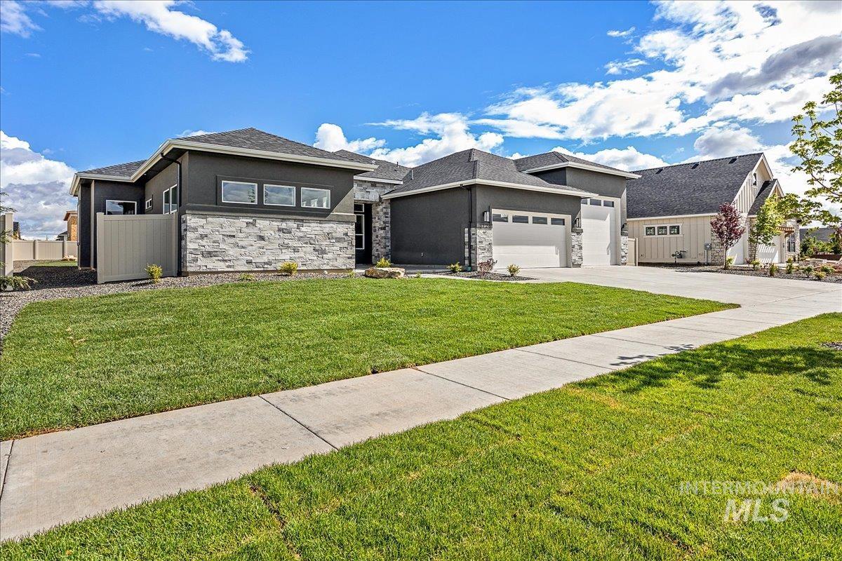 Prairie-style home with an attached garage, concrete driveway, stucco siding, and stone siding