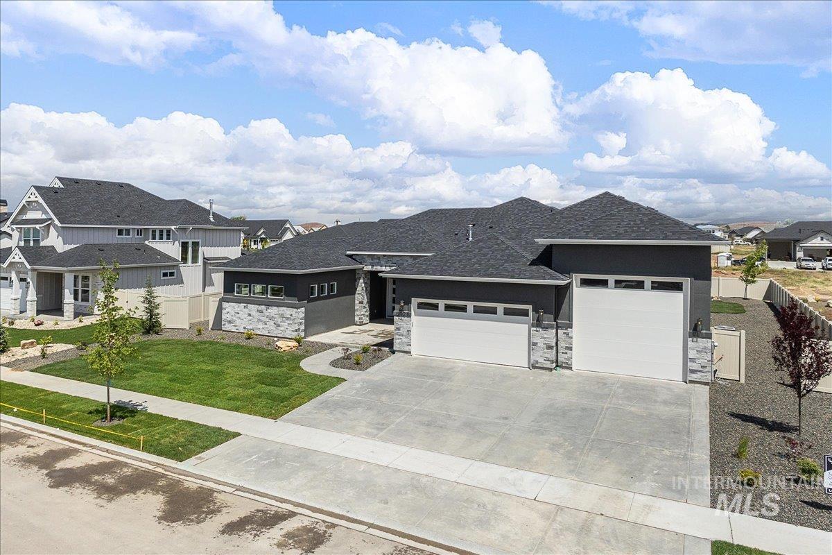 Prairie-style house featuring a garage, stone siding, a residential view, and concrete driveway
