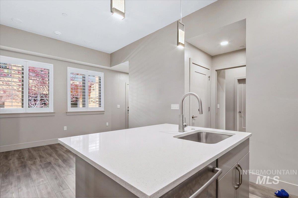 Kitchen island featuring a stainless steel sink with a high-arc faucet, light-toned countertop, and cabinet storage