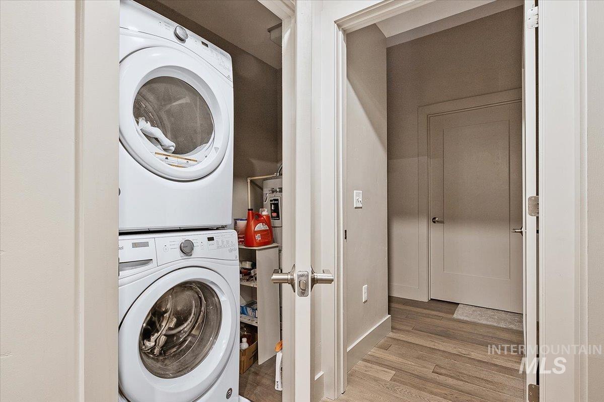 Laundry room featuring stacked washer and dryer and light wood finished floors