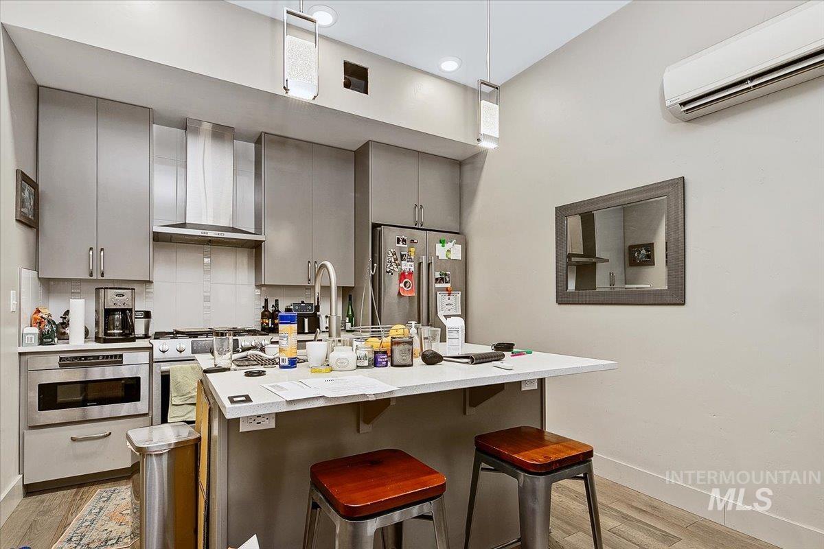 Kitchen featuring gray cabinetry, a breakfast bar, stainless steel appliances, and light wood finished floors
