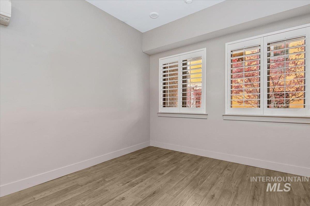 Room featuring two windows with white plantation shutters, wood-finish flooring, and recessed ceiling lighting