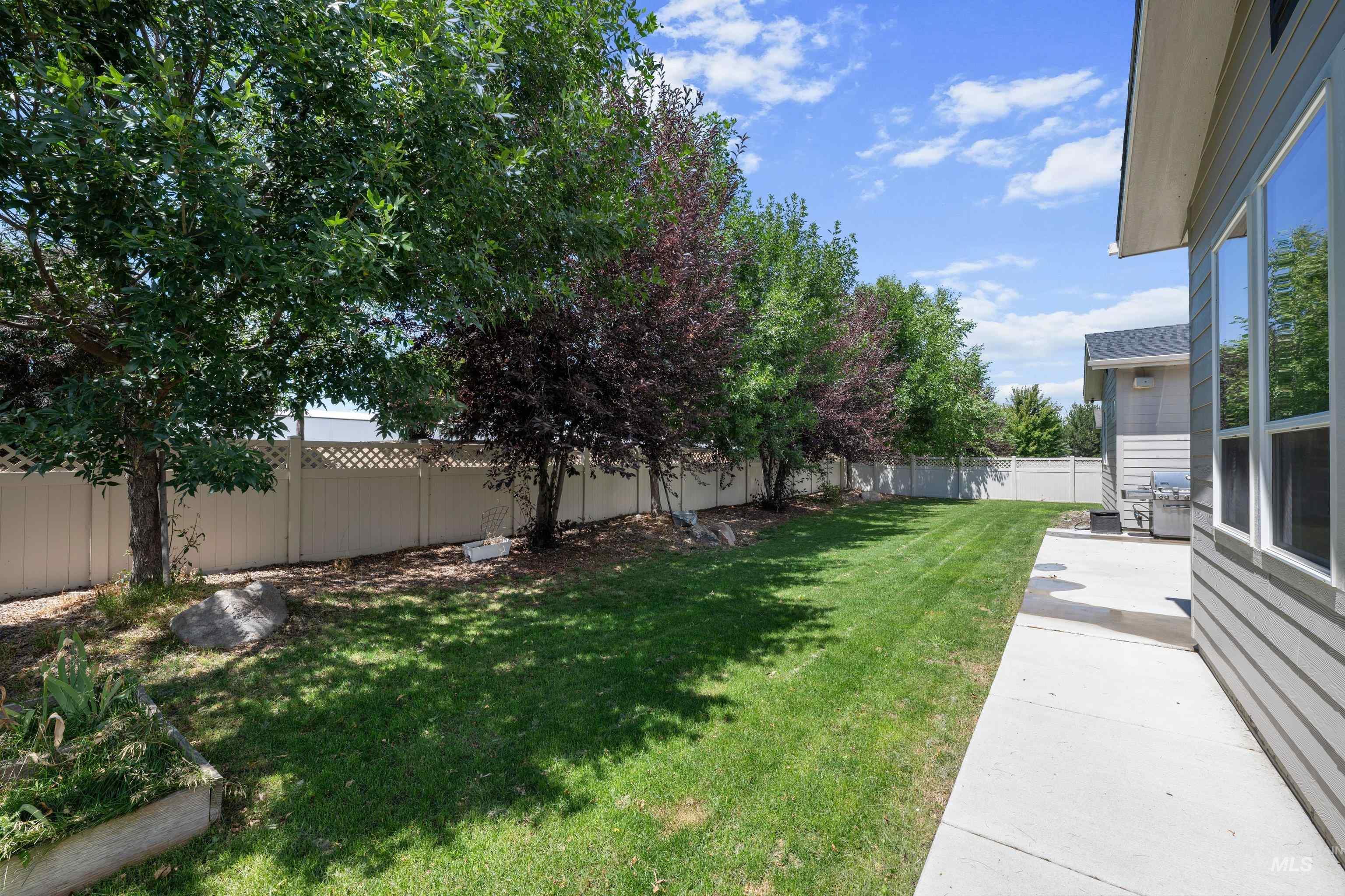 Spacious backyard featuring a manicured lawn, a concrete patio, and a privacy fence with lattice accents