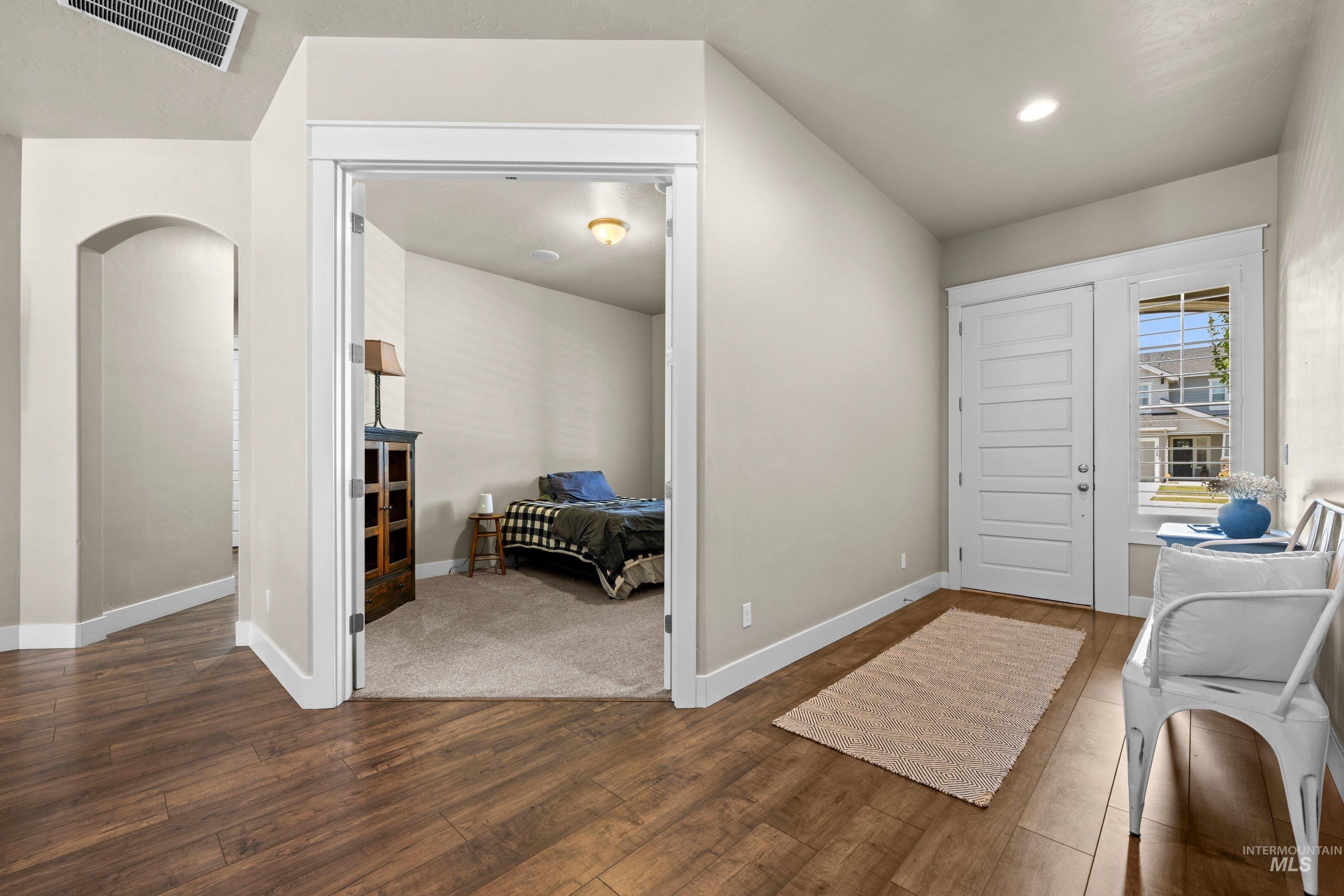 Entryway featuring wood-finish flooring, white paneled door with sidelight, and recessed lighting
