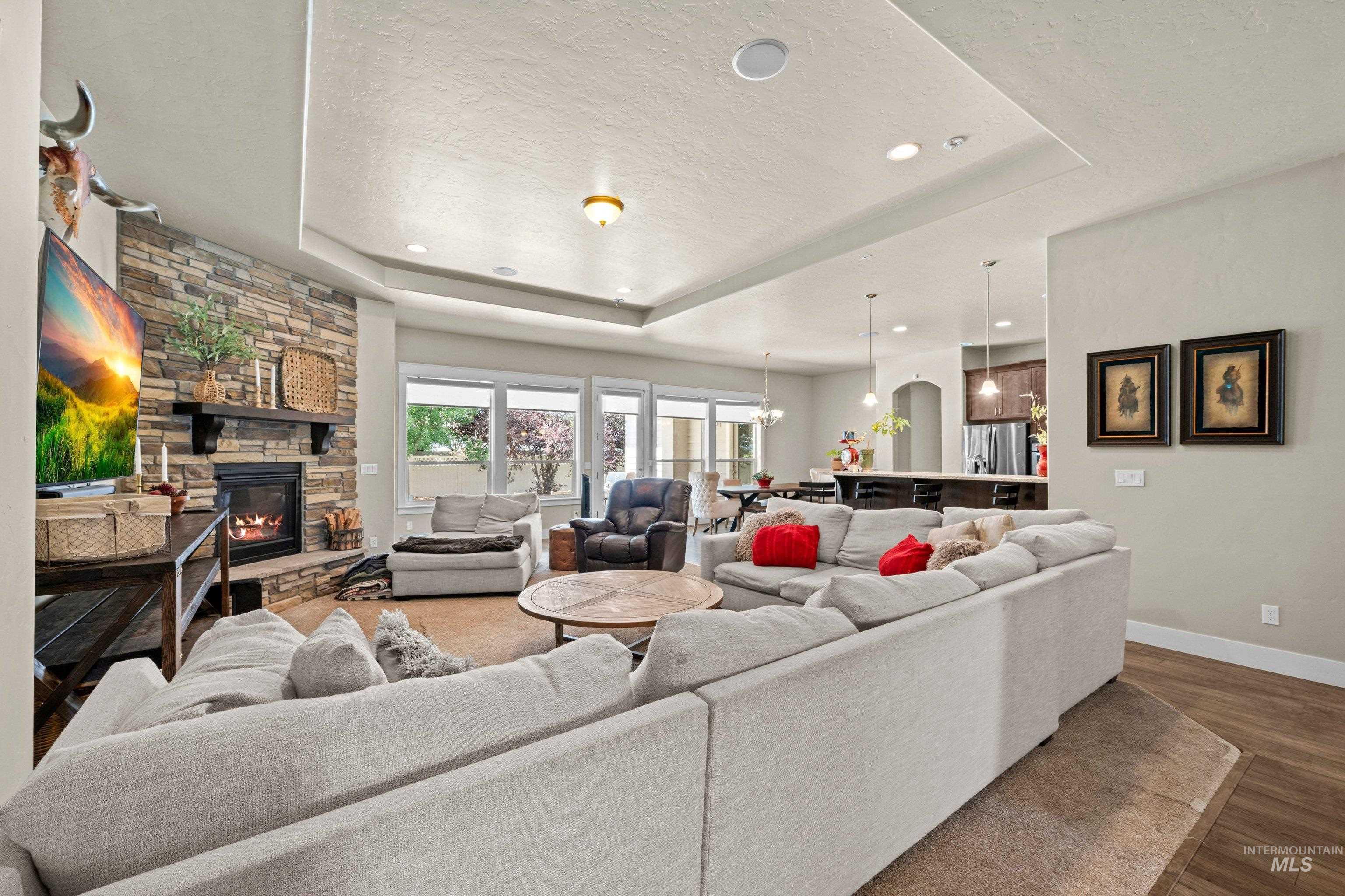 Living space featuring a stone-clad fireplace with a dark wood mantel, recessed lighting, and a tray ceiling