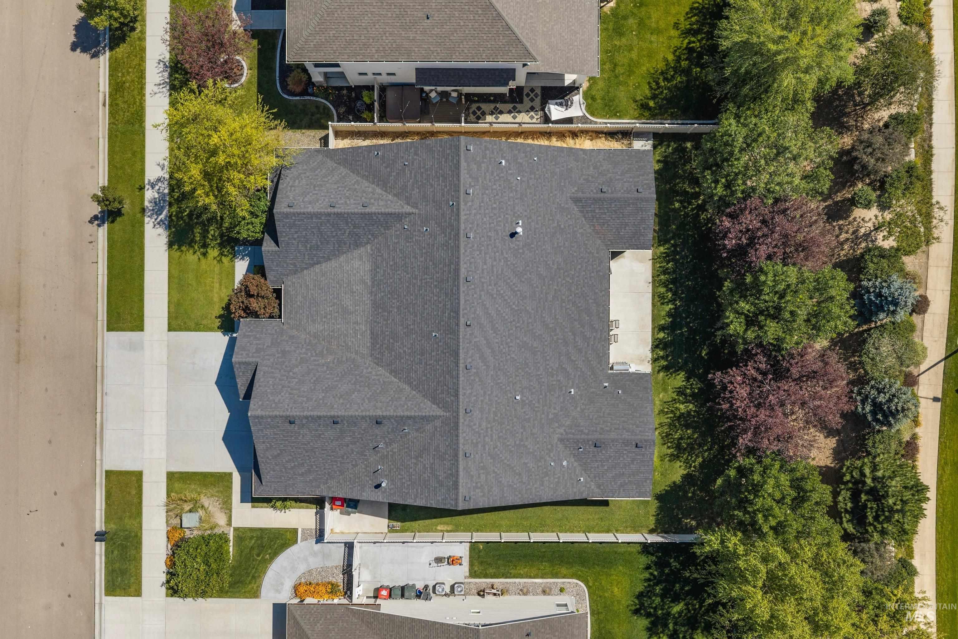 Aerial perspective highlighting the property?s architectural design, dark shingle roof, and expansive concrete driveway