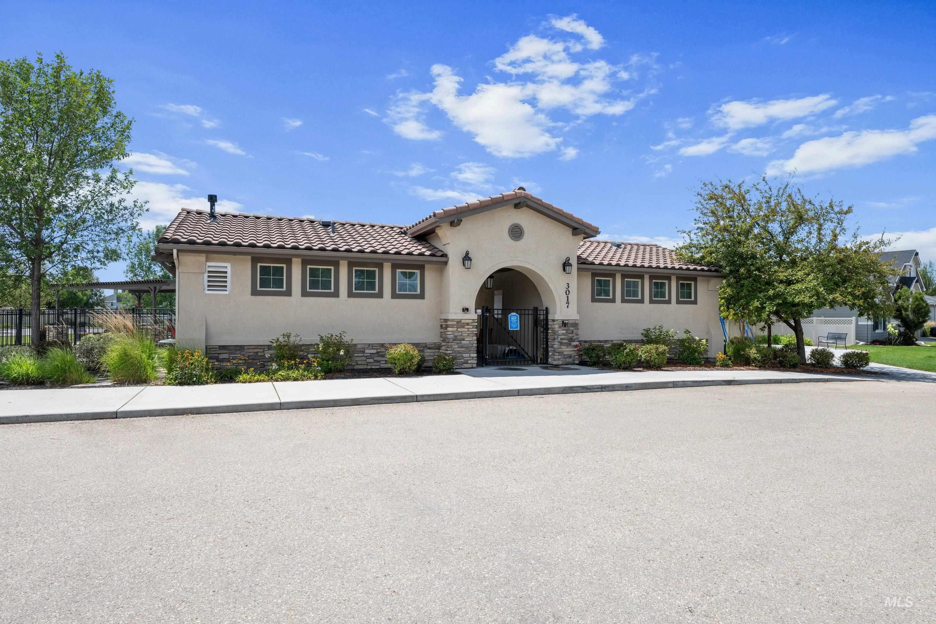 Community amenity building featuring a stucco exterior with stone accents, arched entry, and a tile roof