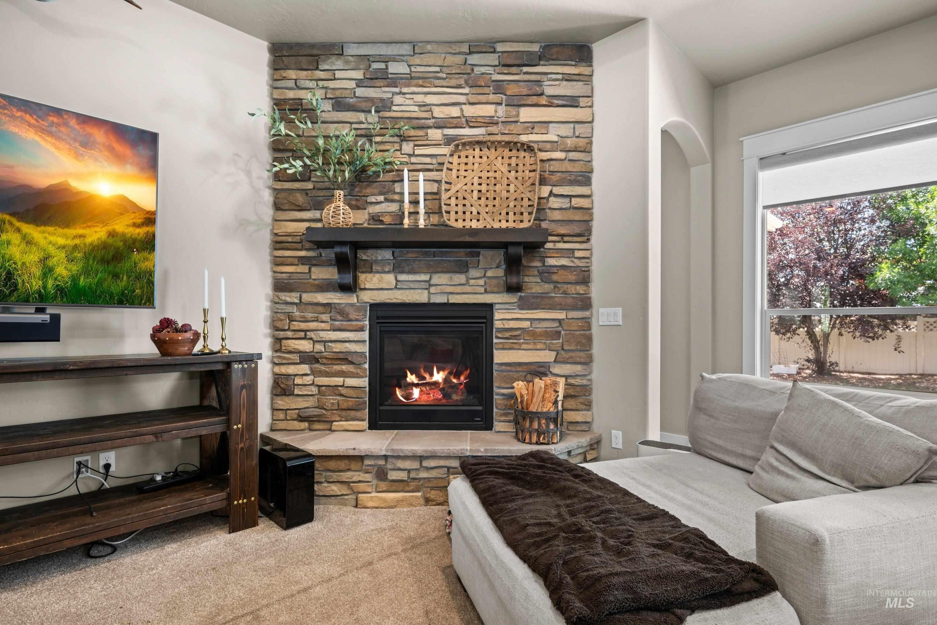 Stacked stone fireplace with a dark wood mantel and hearth