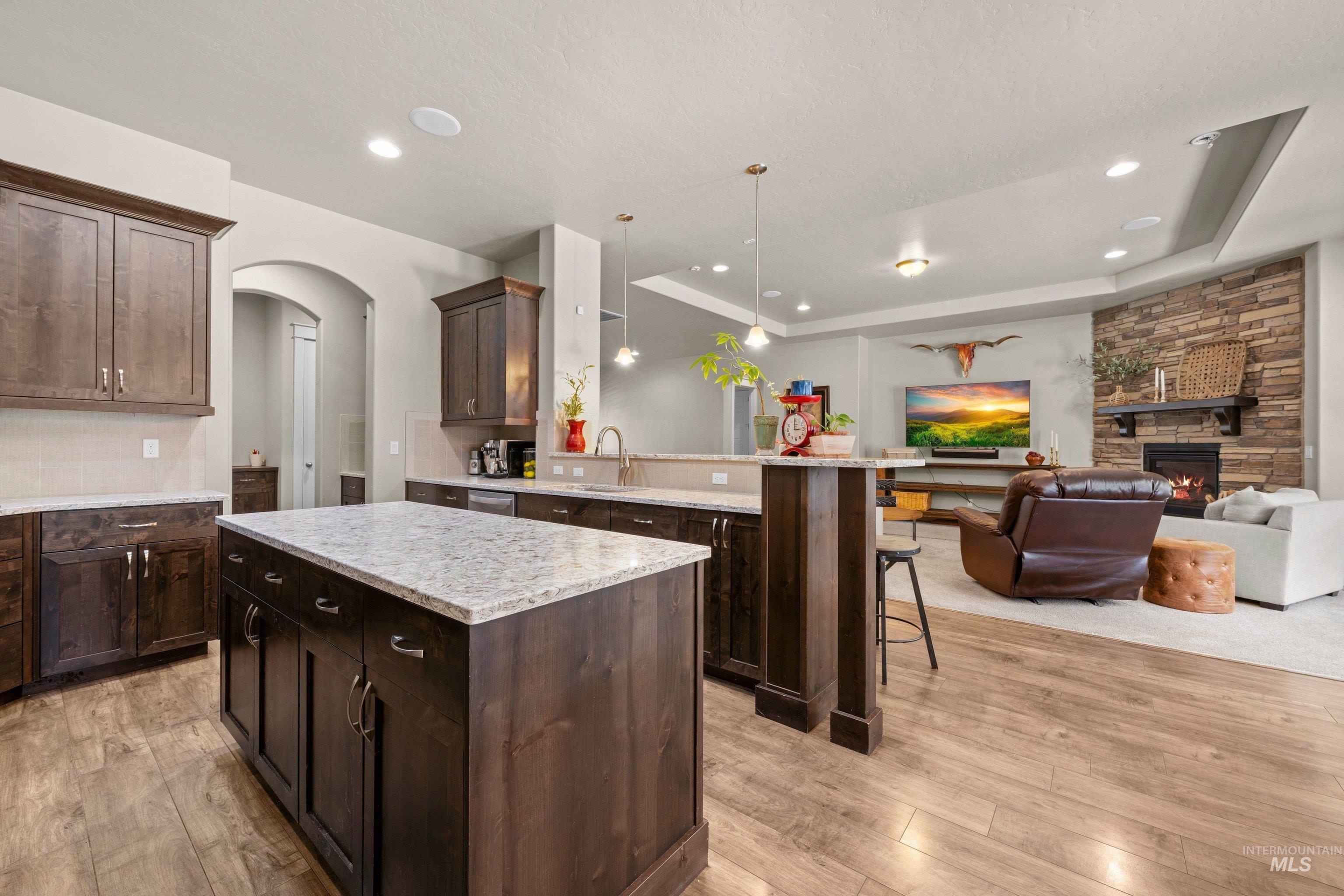 Open-concept living space featuring a kitchen with a large island, dark wood cabinetry, and light-toned countertops