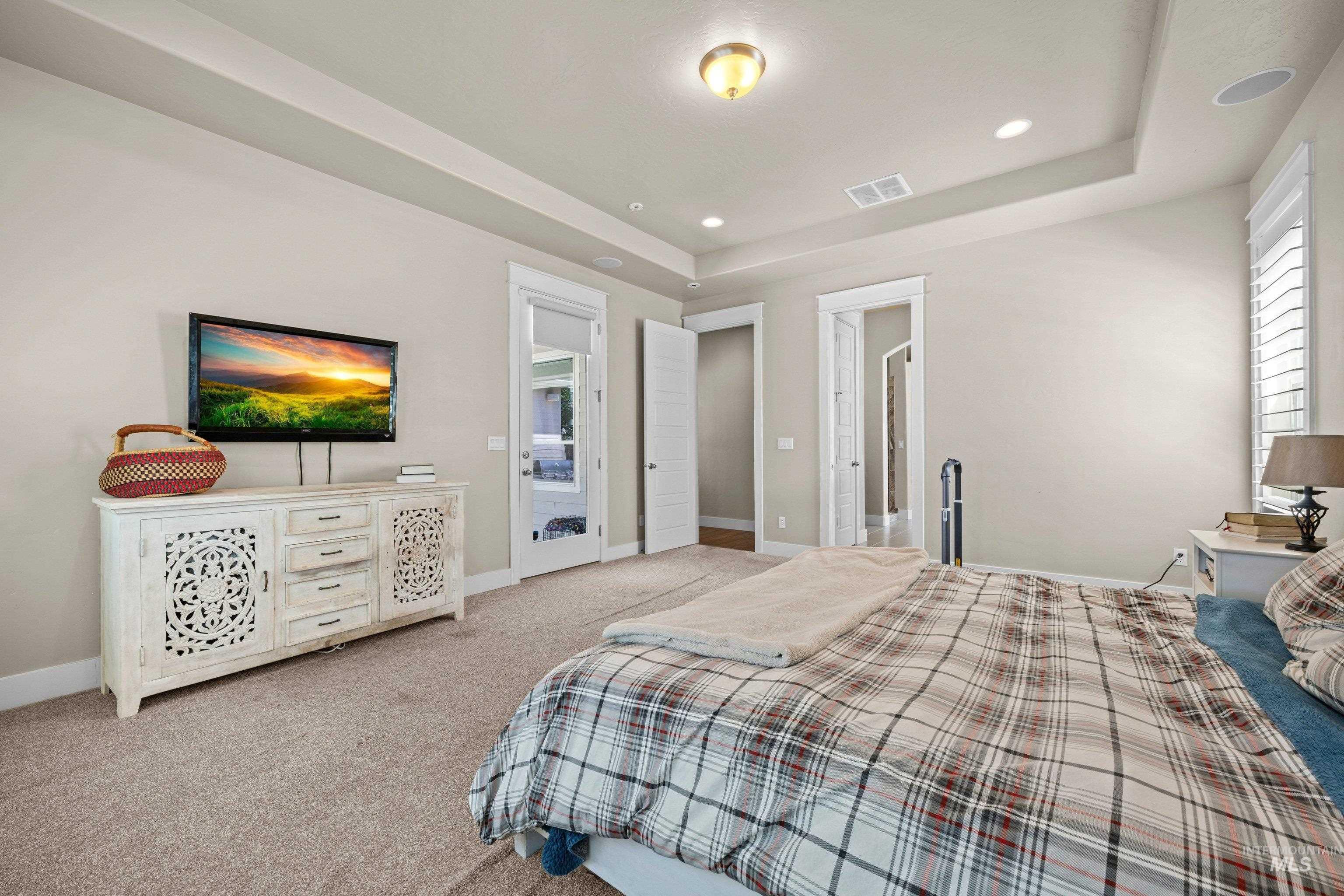 Carpeted room featuring a tray ceiling with recessed lighting, an overhead light fixture, and white plantation shutters