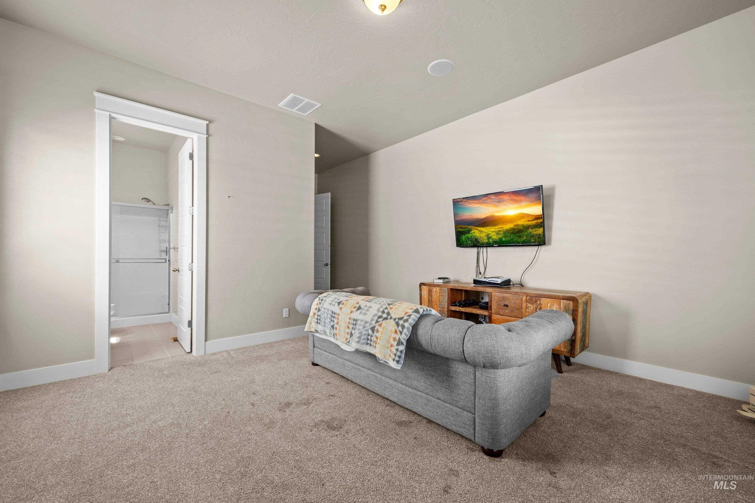 Carpeted room with a full bathroom featuring a glass-enclosed shower
