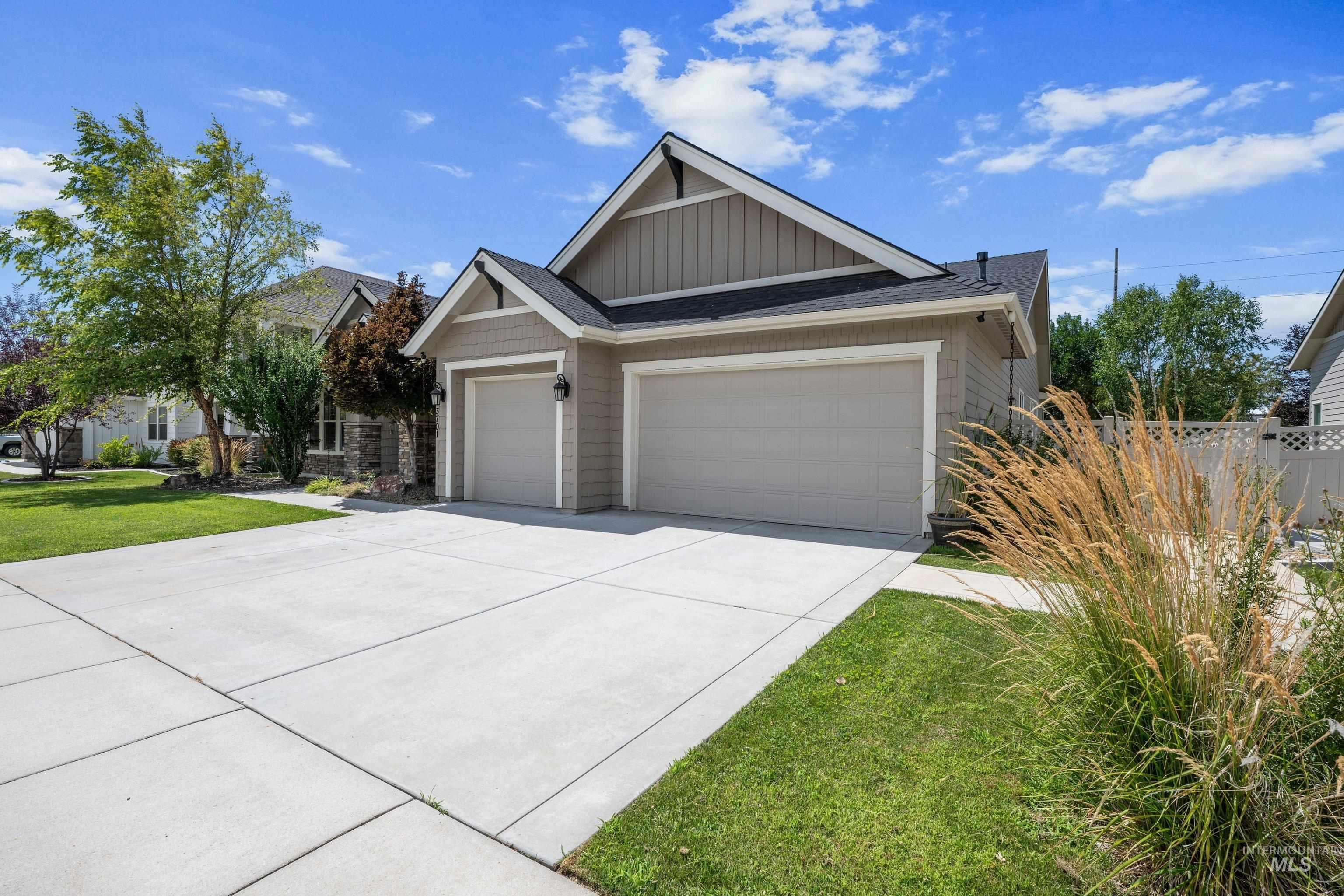 Exterior featuring a two-car garage, concrete driveway, and natural siding with stone accents