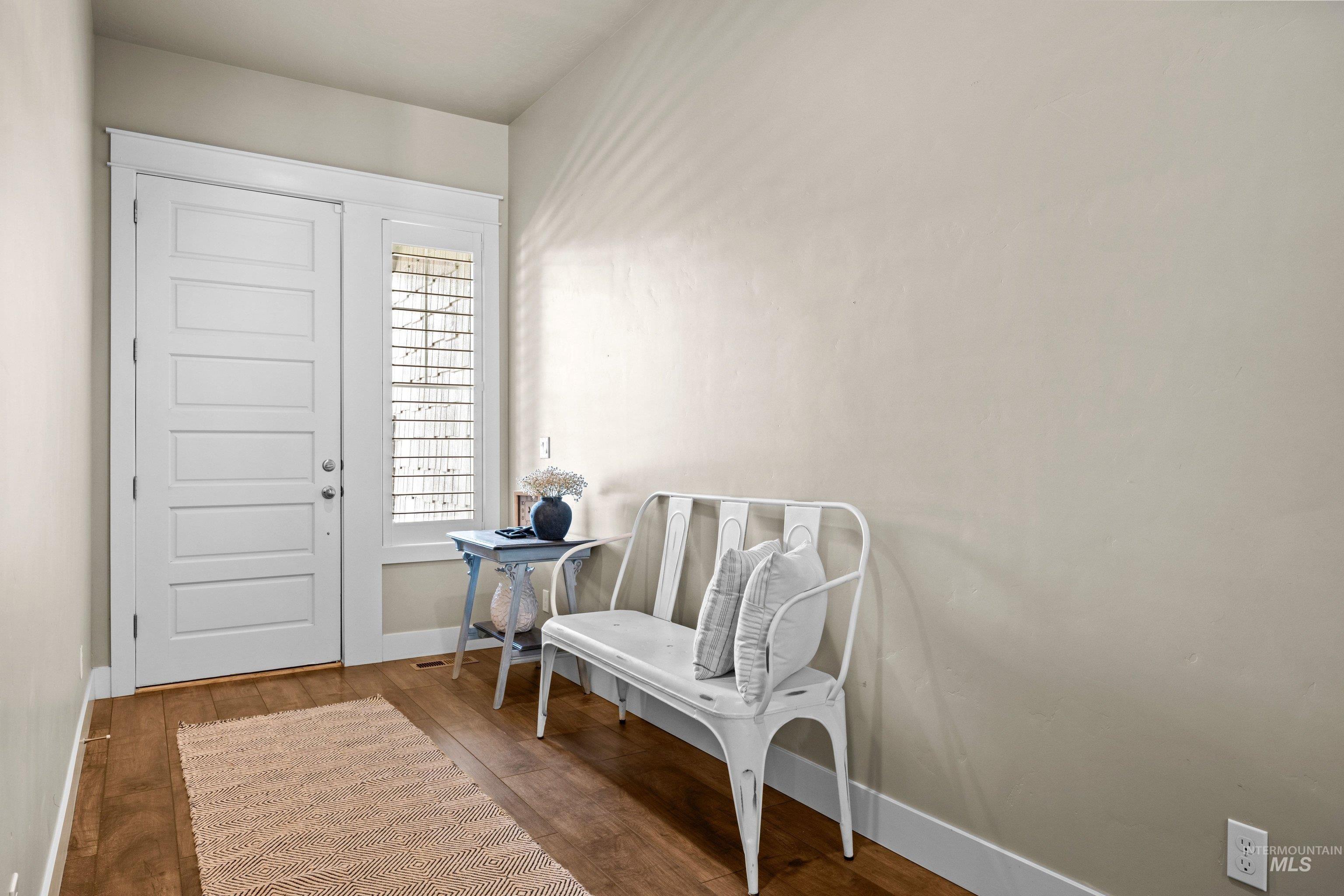 Entryway with wood-finish flooring, a white paneled door, and a sidelight with horizontal blinds
