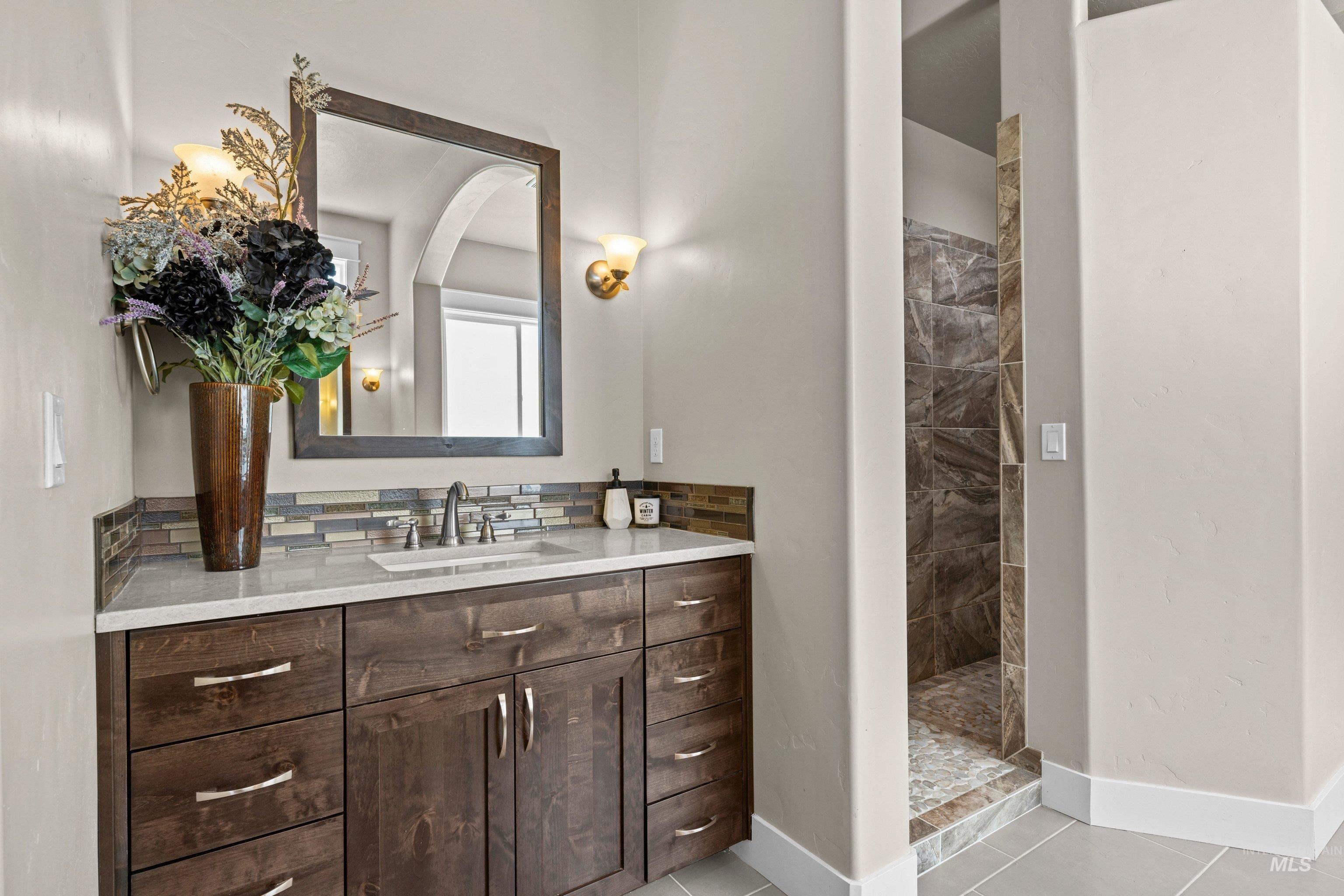 Vanity featuring a white countertop, undermount sink, and dark wood-finish cabinetry with silver hardware