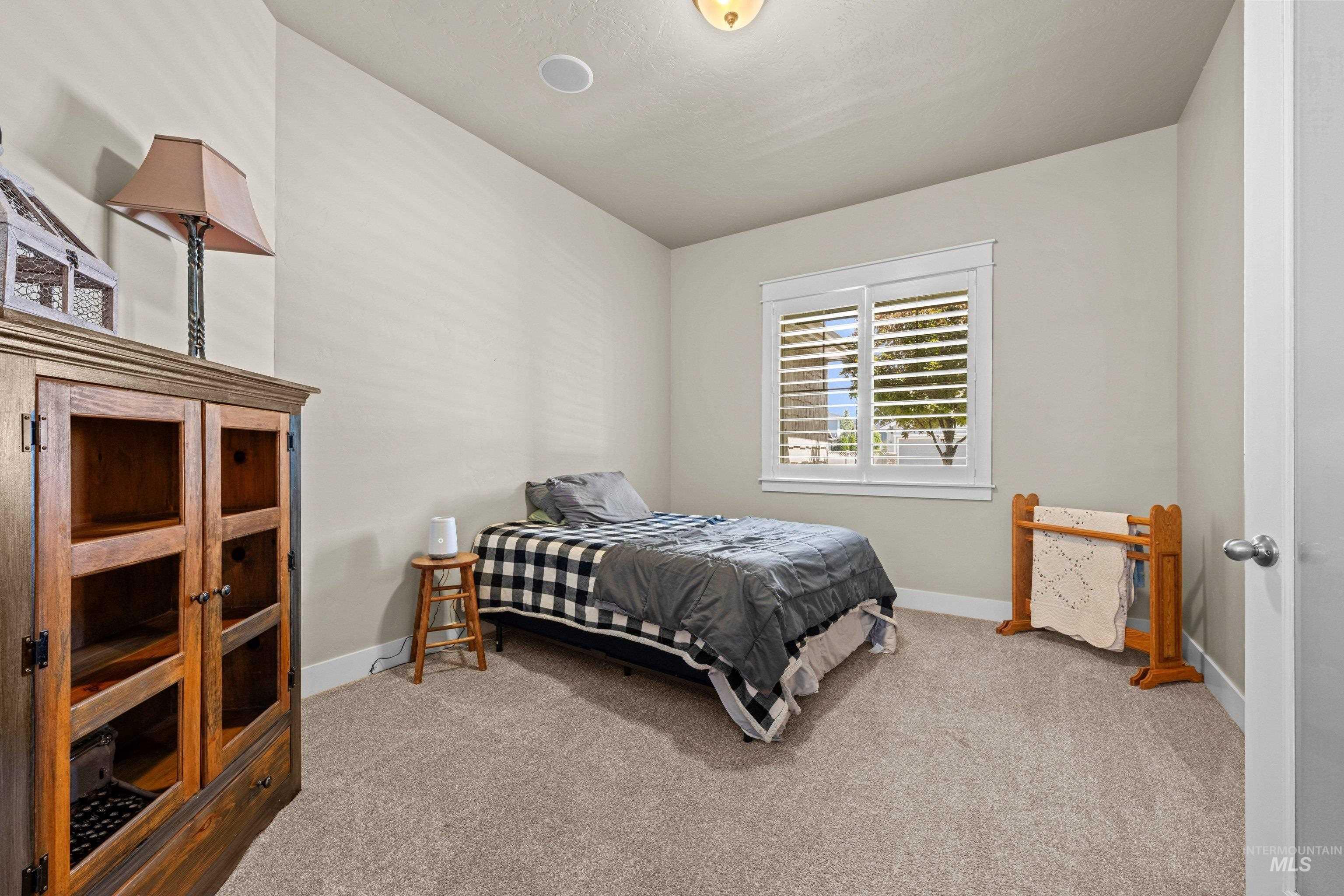 Carpeted room featuring a window with plantation shutters, a recessed ceiling light, and a surface-mounted light fixture